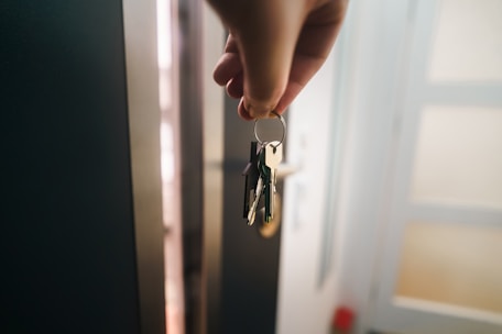 A hand holds a keyring near an open door.