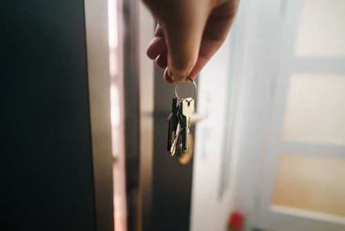 A hand holds a keyring near an open door