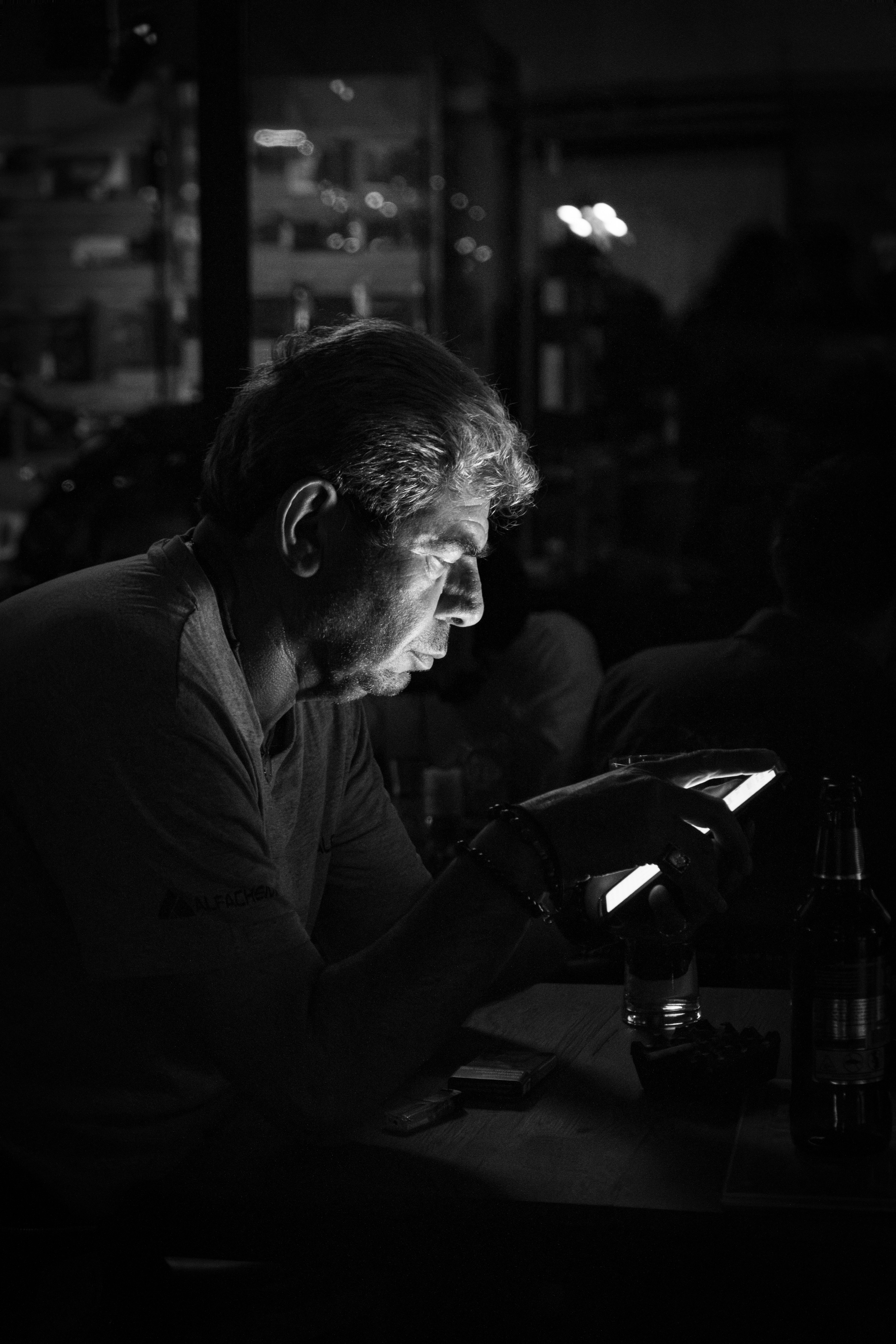 A man uses his phone in dim lighting.