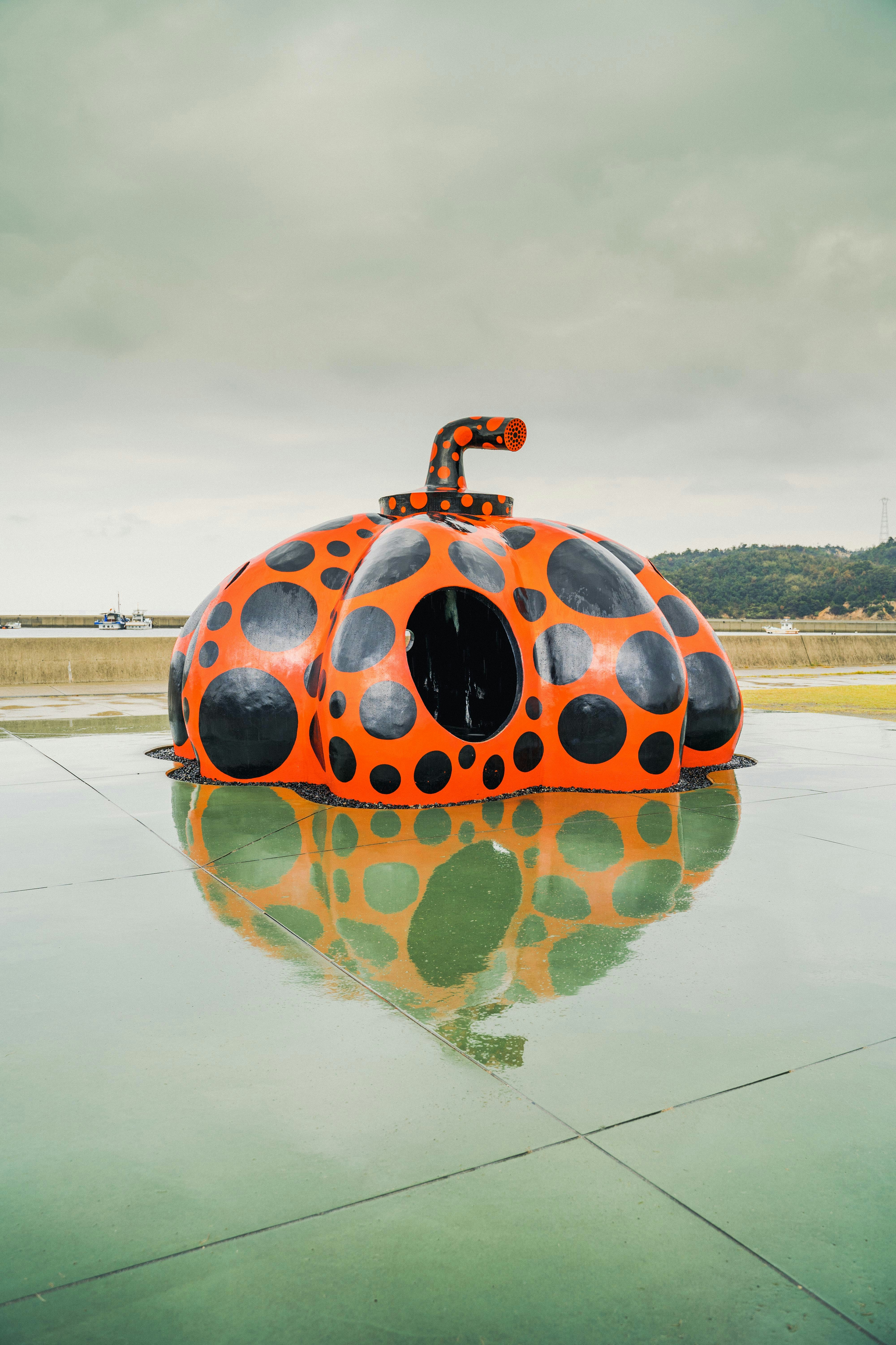A pumpkin sculpture reflects in the water.
