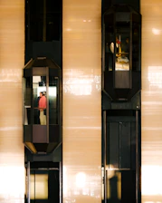 Two elevators are moving up and down a building.