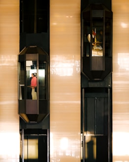 Two elevators are moving up and down a building.