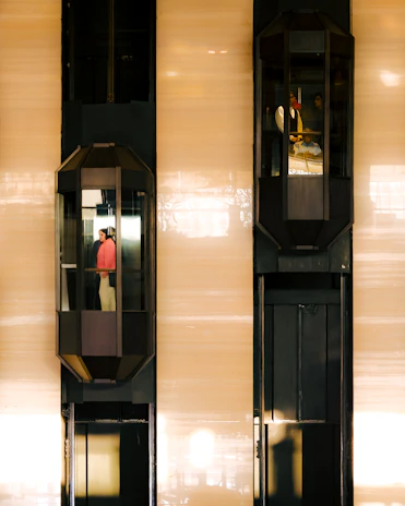 Two elevators are moving up and down a building.