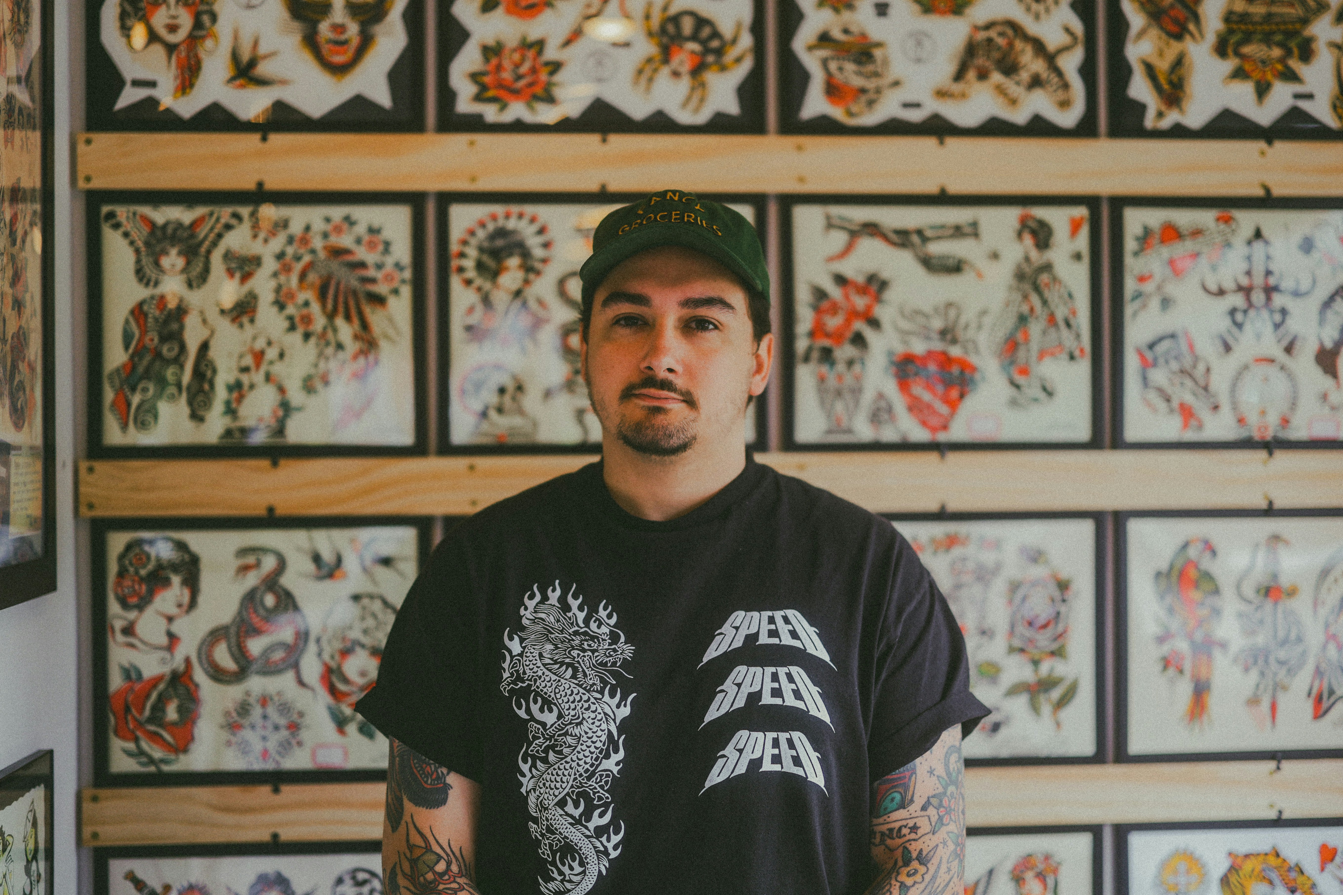 A tattoo artist stands in front of his work.