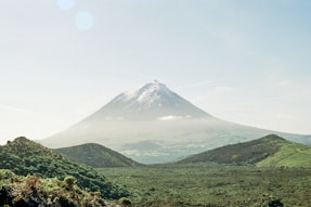 A mountain rises above lush green landscapes.