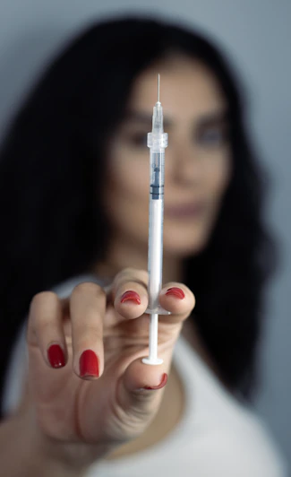 A person is holding up a syringe