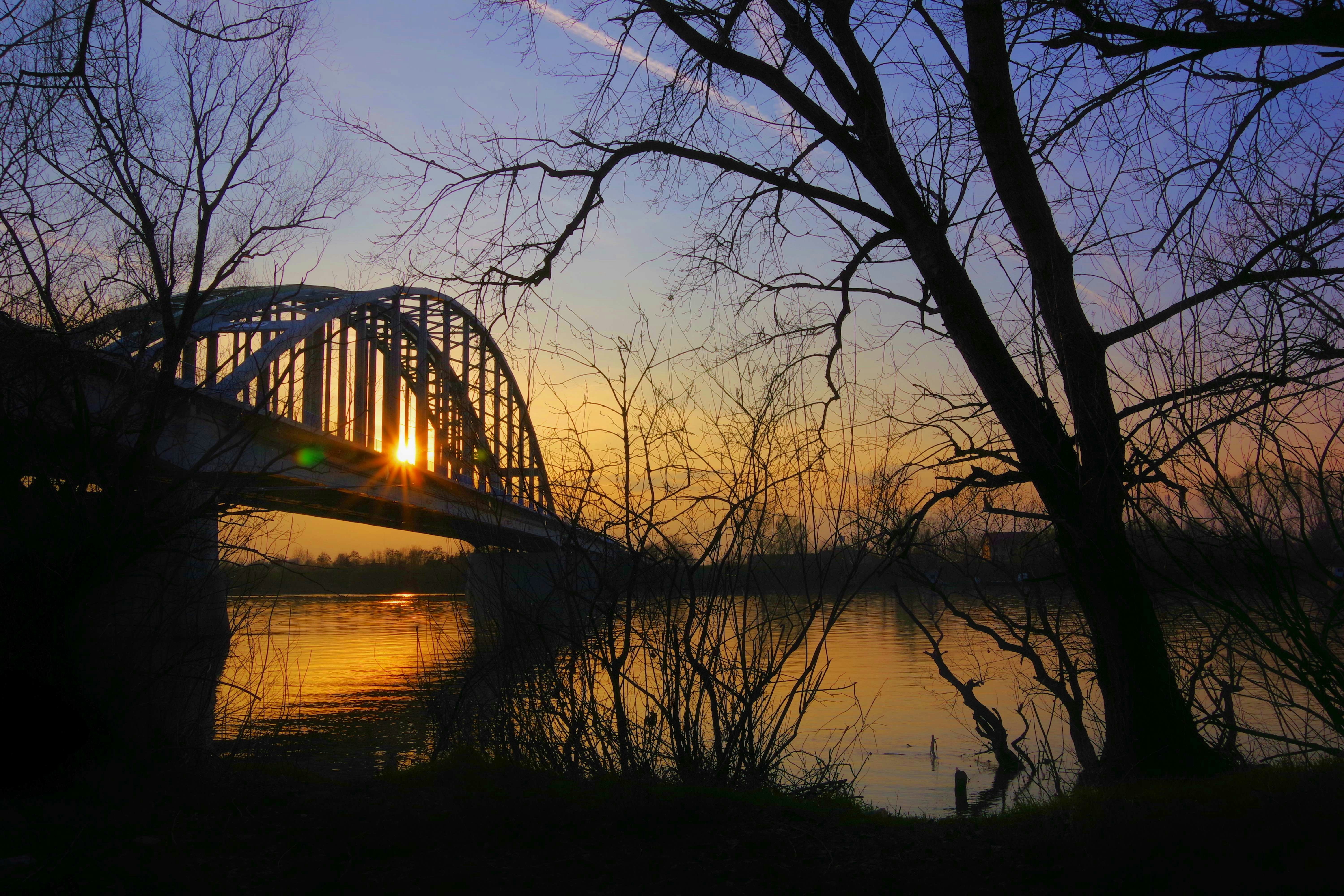 Sunset illuminates a bridge over a serene lake.
