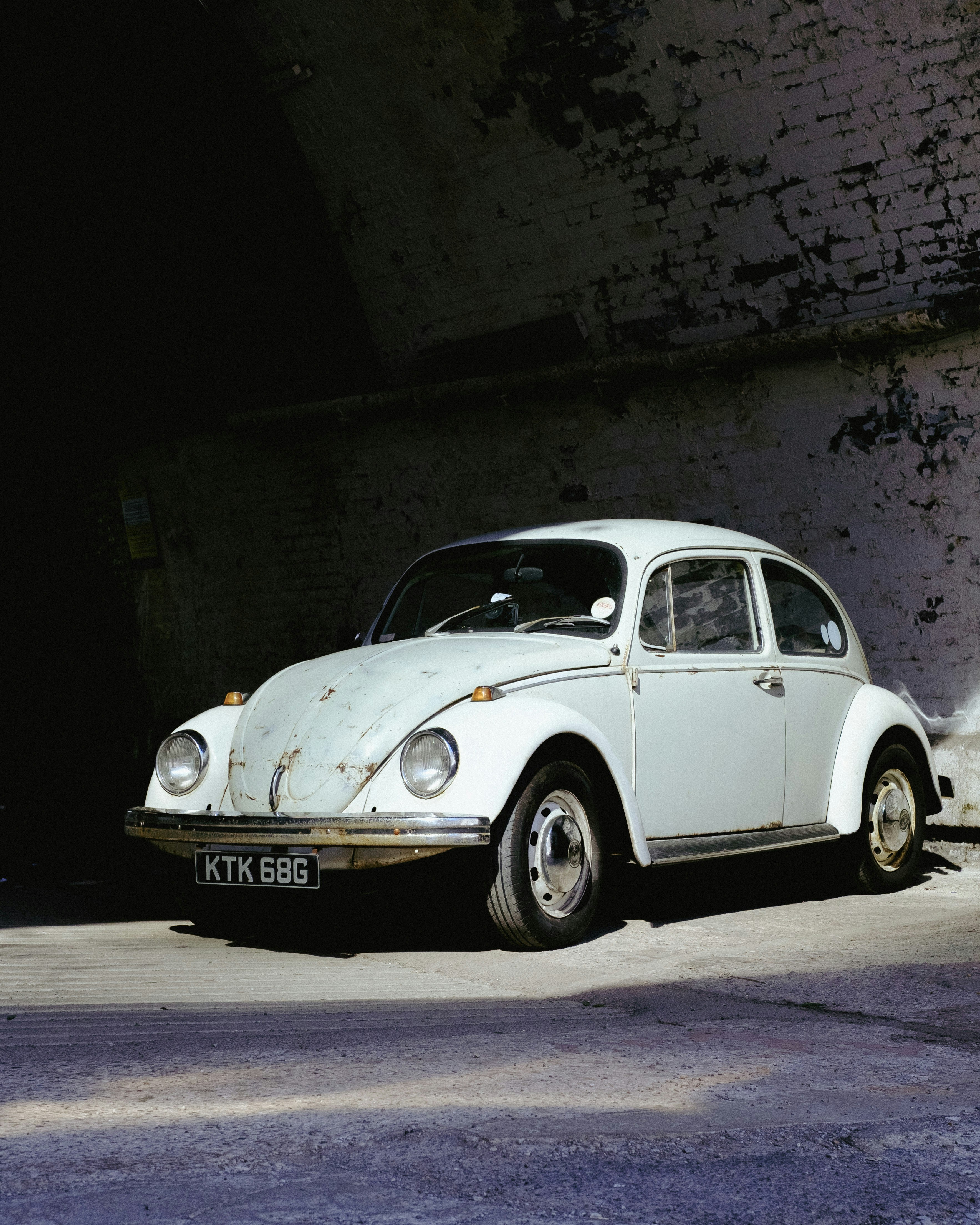 A white volkswagen beetle sits in a tunnel.