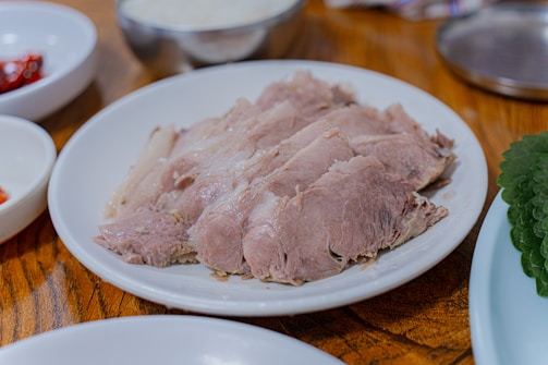 Sliced cooked meat served on a white plate.