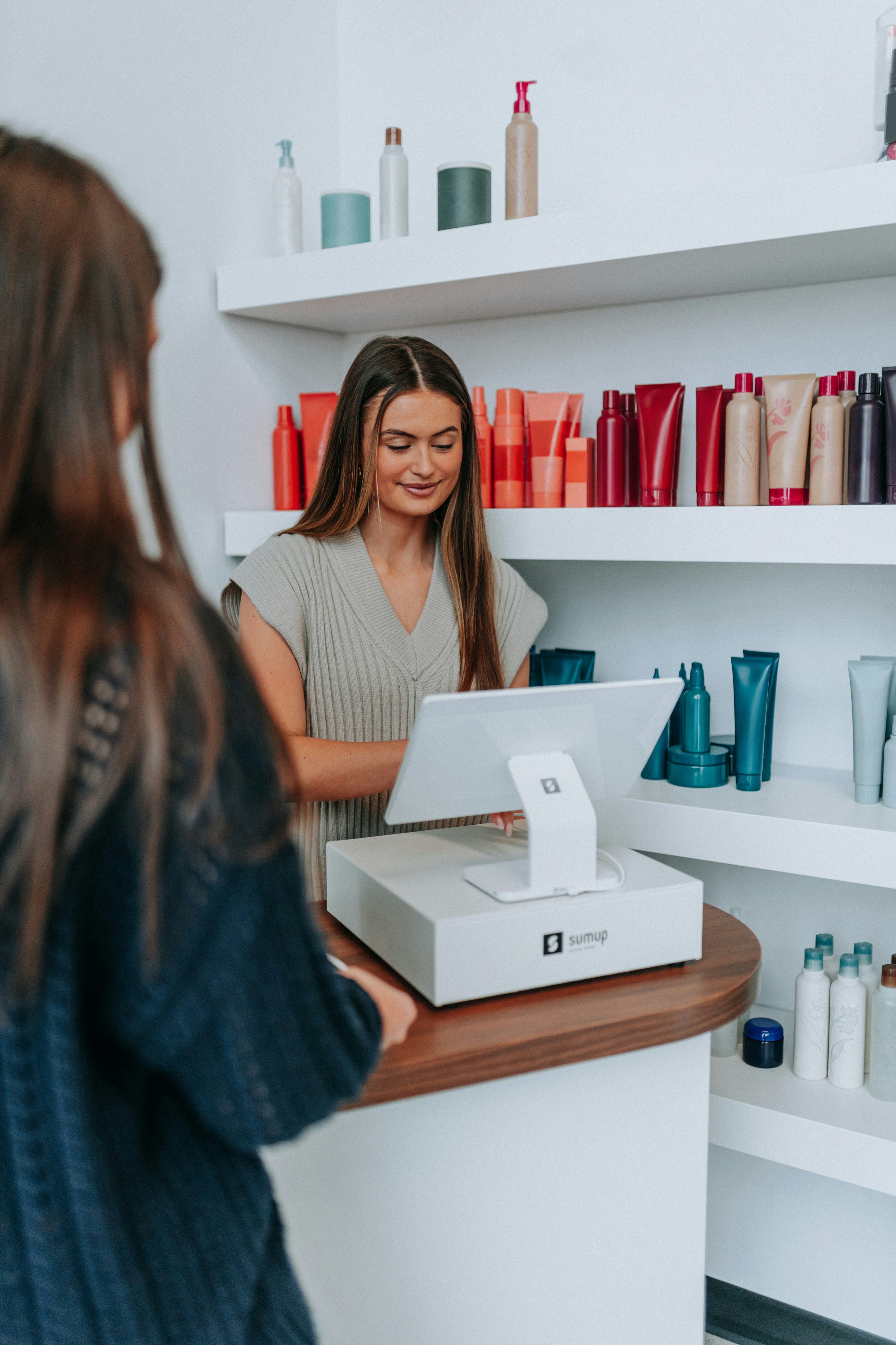 A hairstylist checks out a customer at the register.