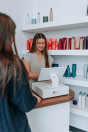 A hairstylist checks out a customer at the register.