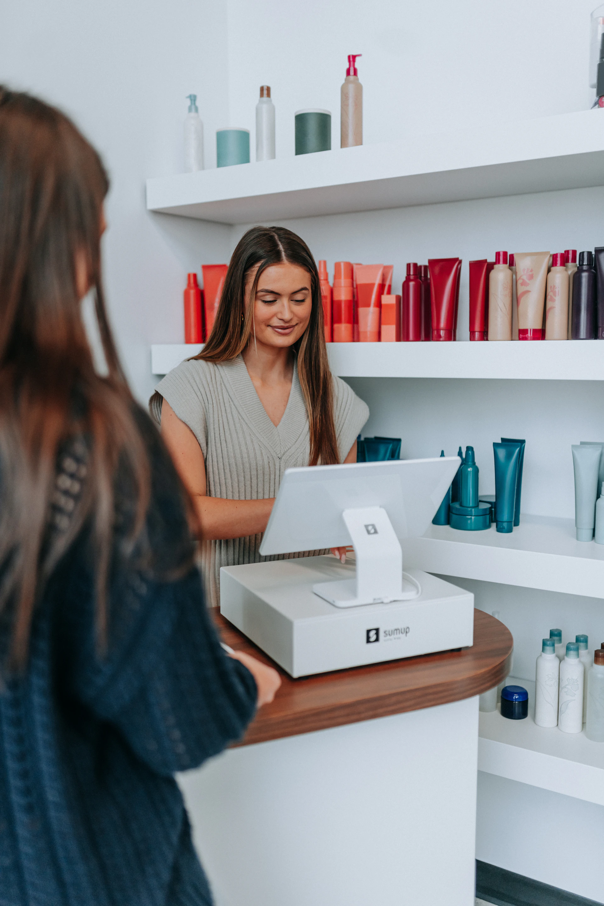 A hairstylist checks out a customer at the register.