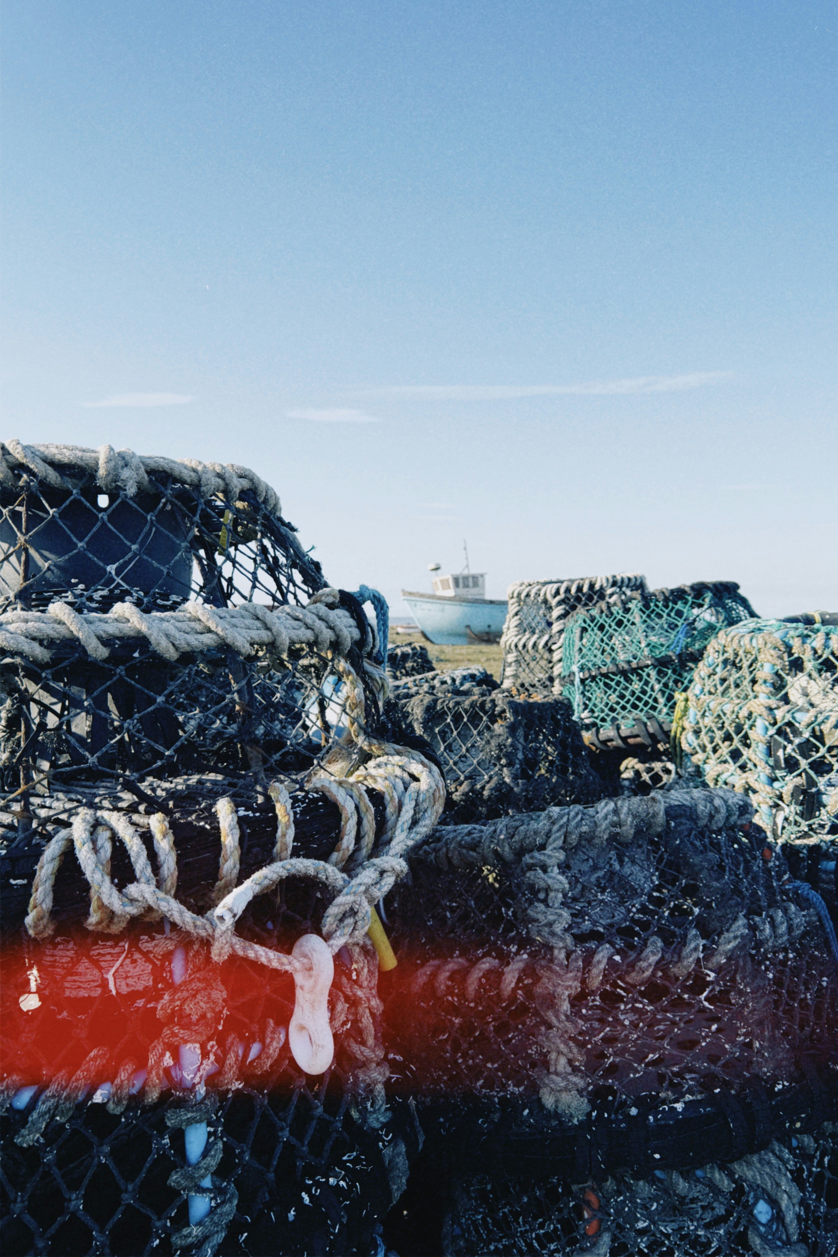 Lobster traps stacked near a boat on the coast