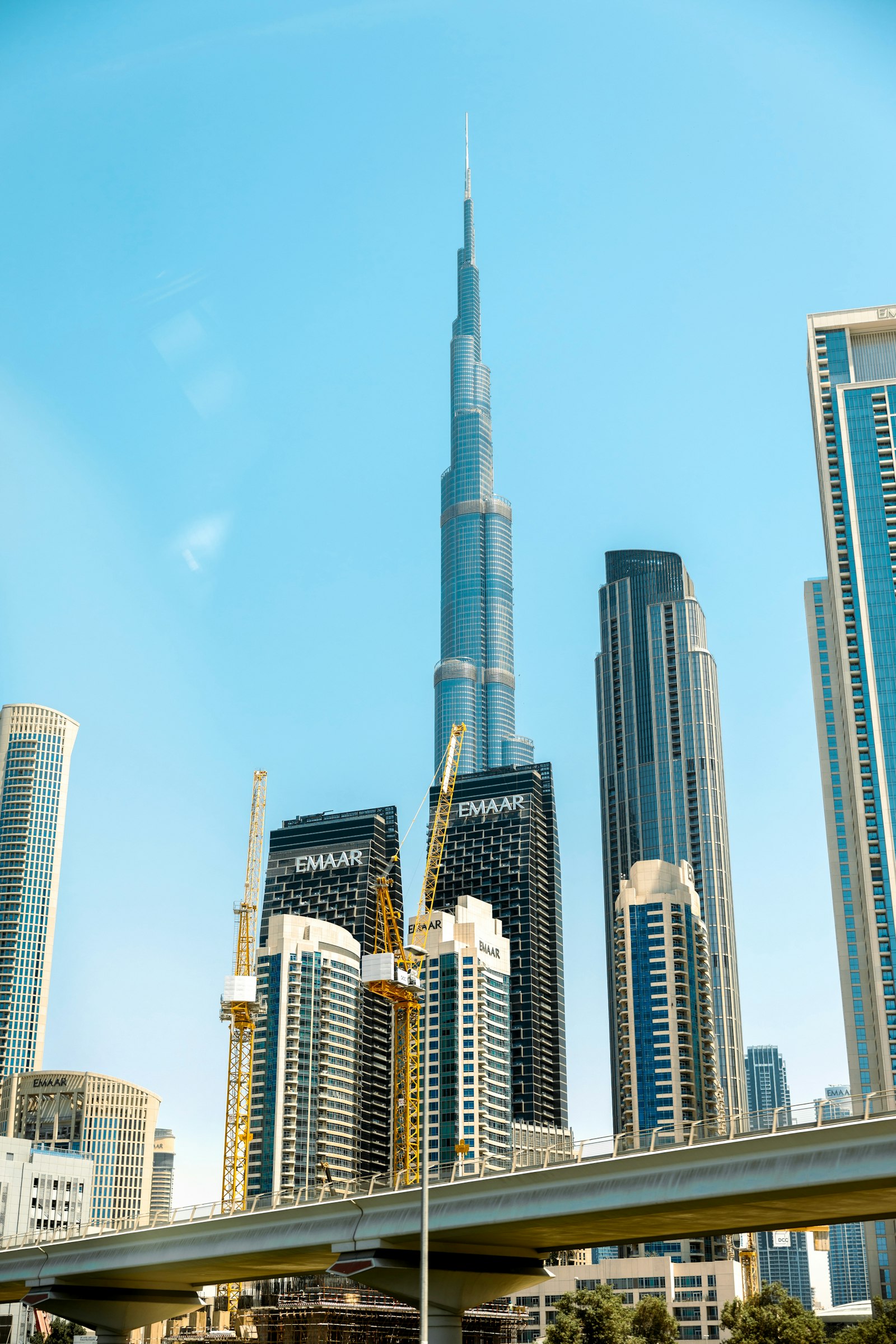 The Burj Khalifa towers over Downtown Dubai's skyline of glass high-rises under a clear blue sky