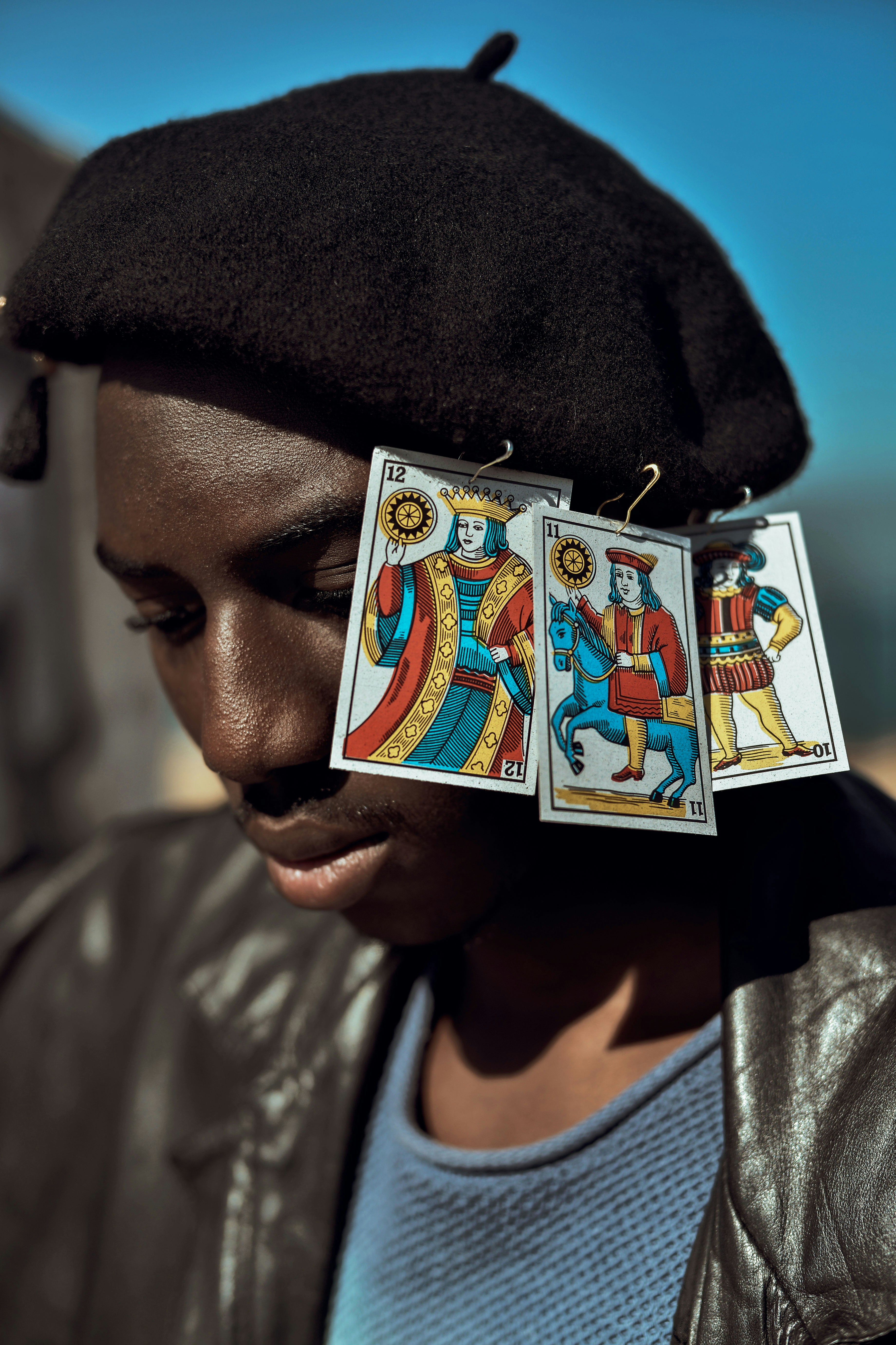 Un hombre lleva una boina con pendientes de naipes.