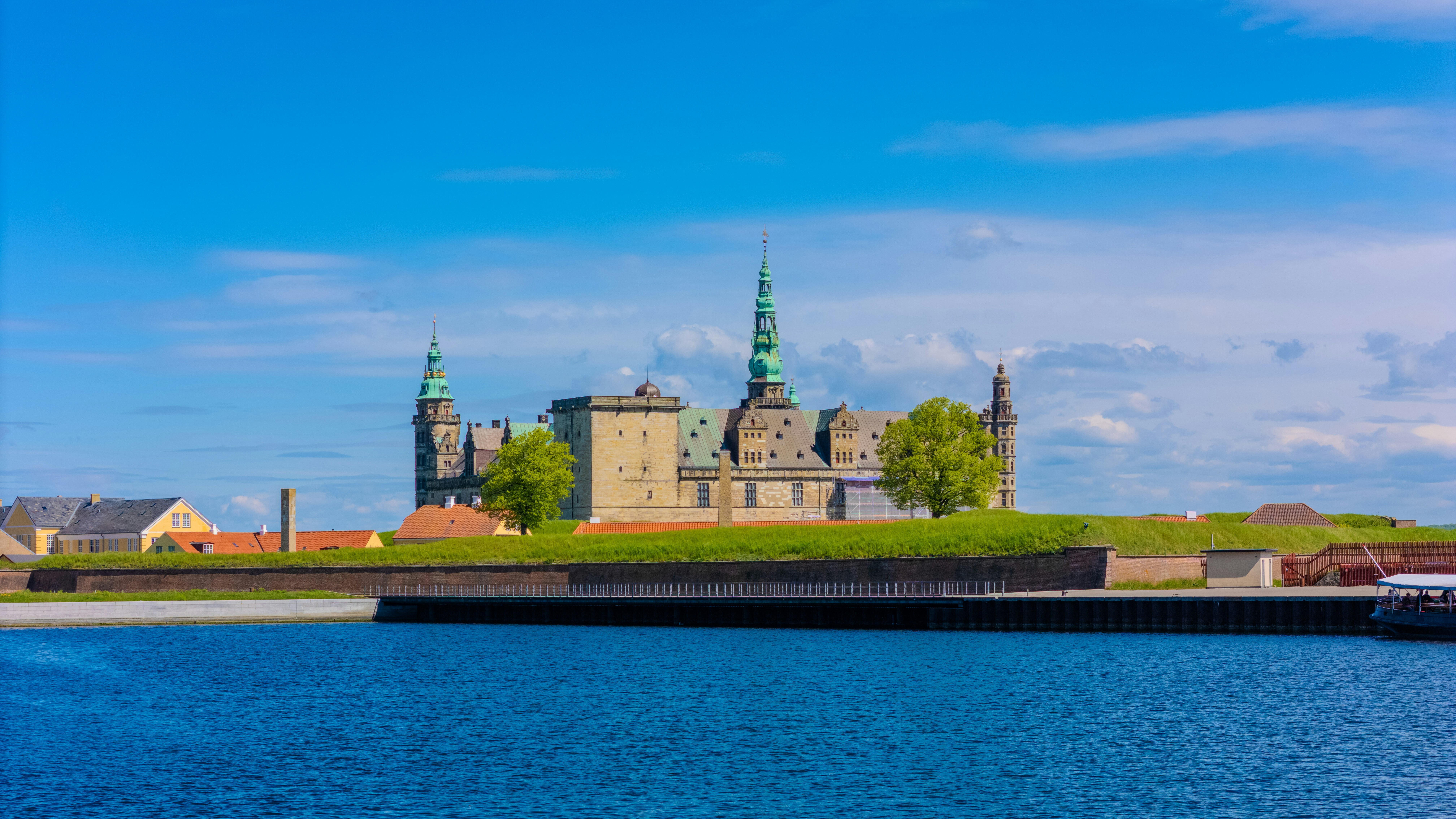 A castle sits by the water under a blue sky.