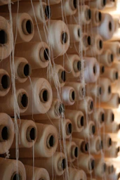 Spools of thread are stored on a wooden shelf.