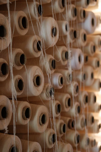 Spools of thread are stored on a wooden shelf.