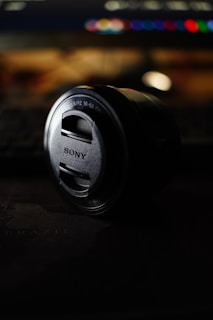 A sony camera lens rests on a dark surface.