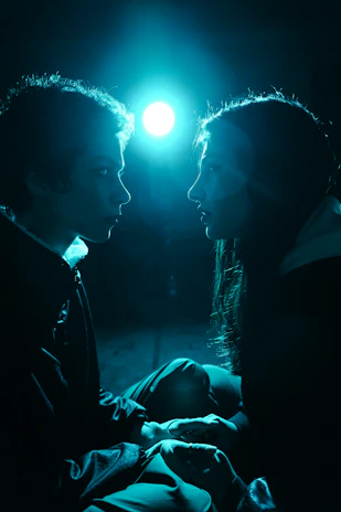 Two people gaze upon something under a blue light.