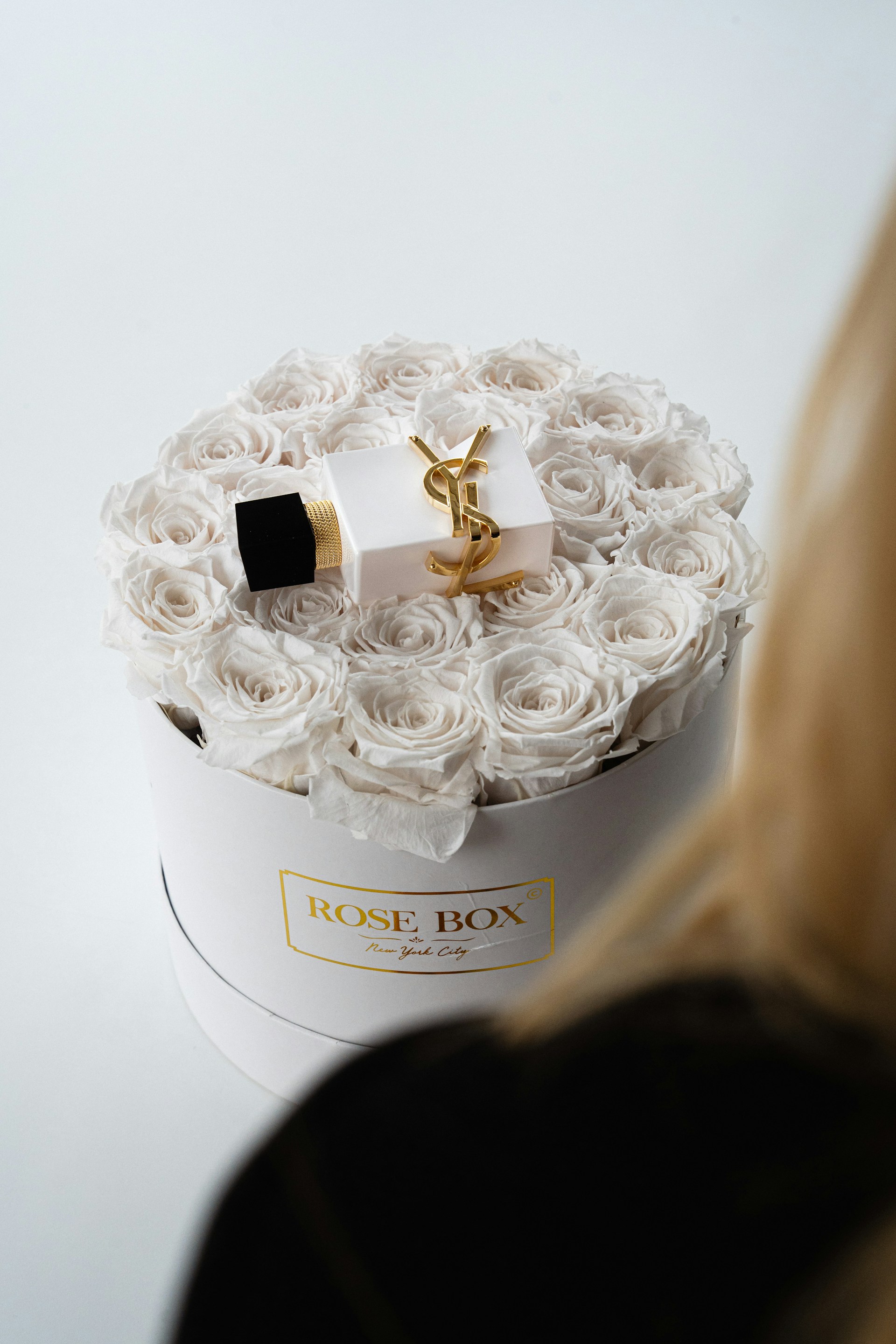 Perfume bottle atop a rose box flower arrangement.