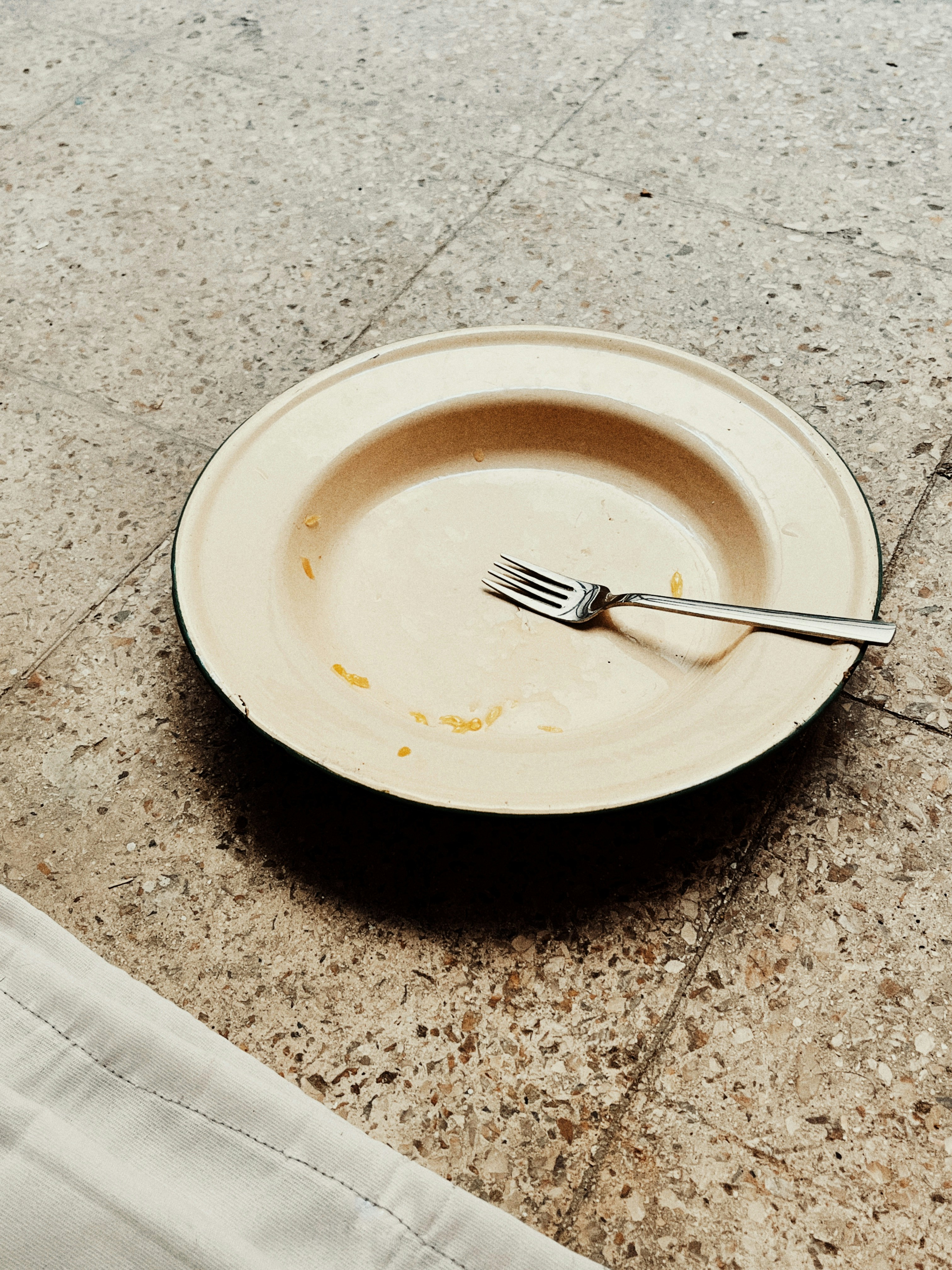Empty plate with fork left on the floor.