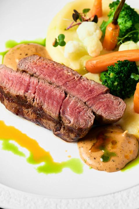 Medium-rare steak served with colorful vegetables.