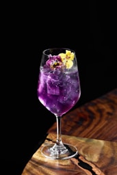 A colorful purple cocktail is adorned with flowers.