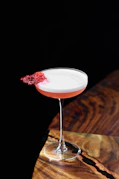 A cocktail garnished with a red, crispy element.
