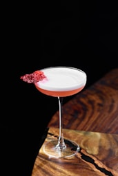 A cocktail garnished with a red, crispy element.