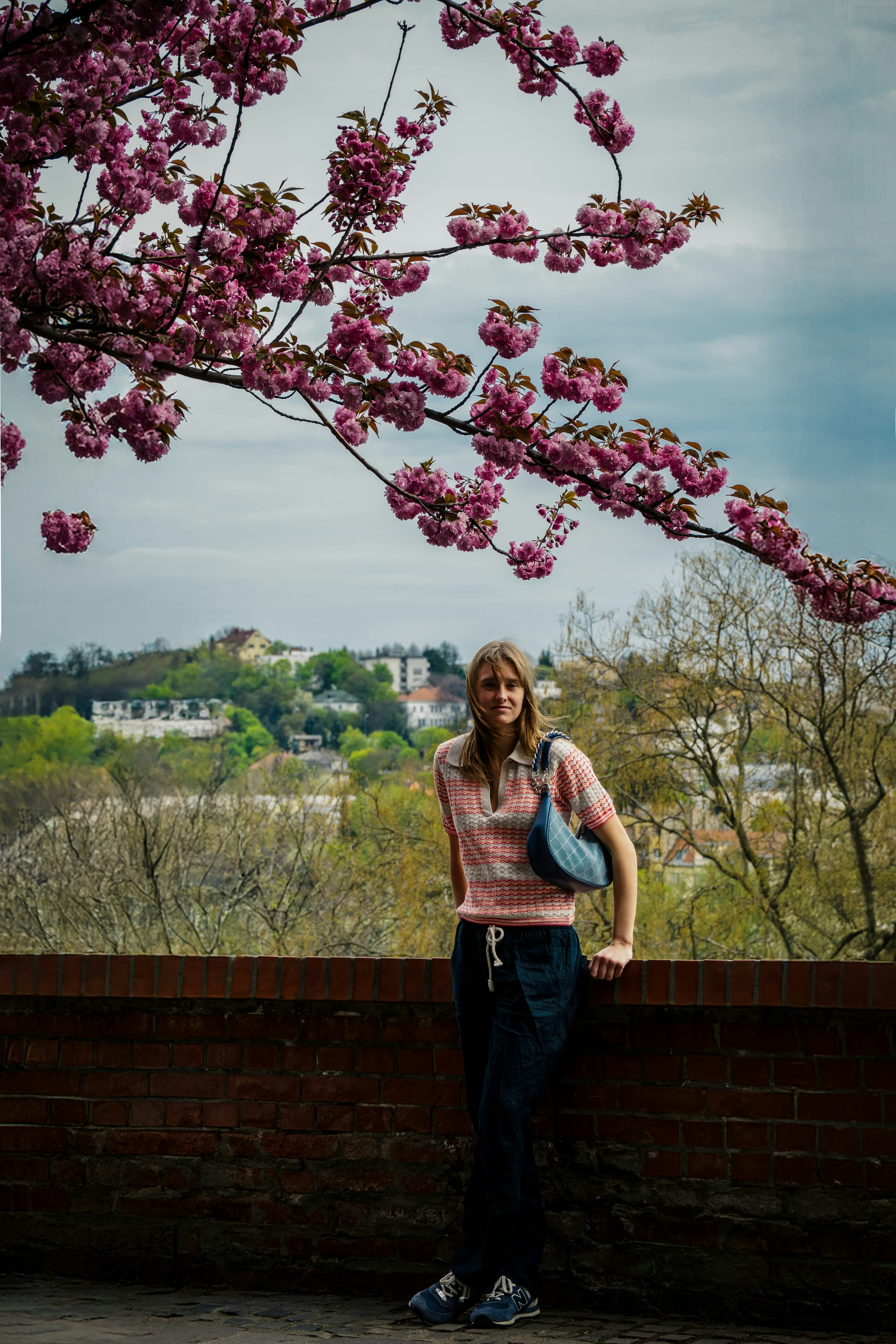 La mujer posa bajo un cerezo en flor.
