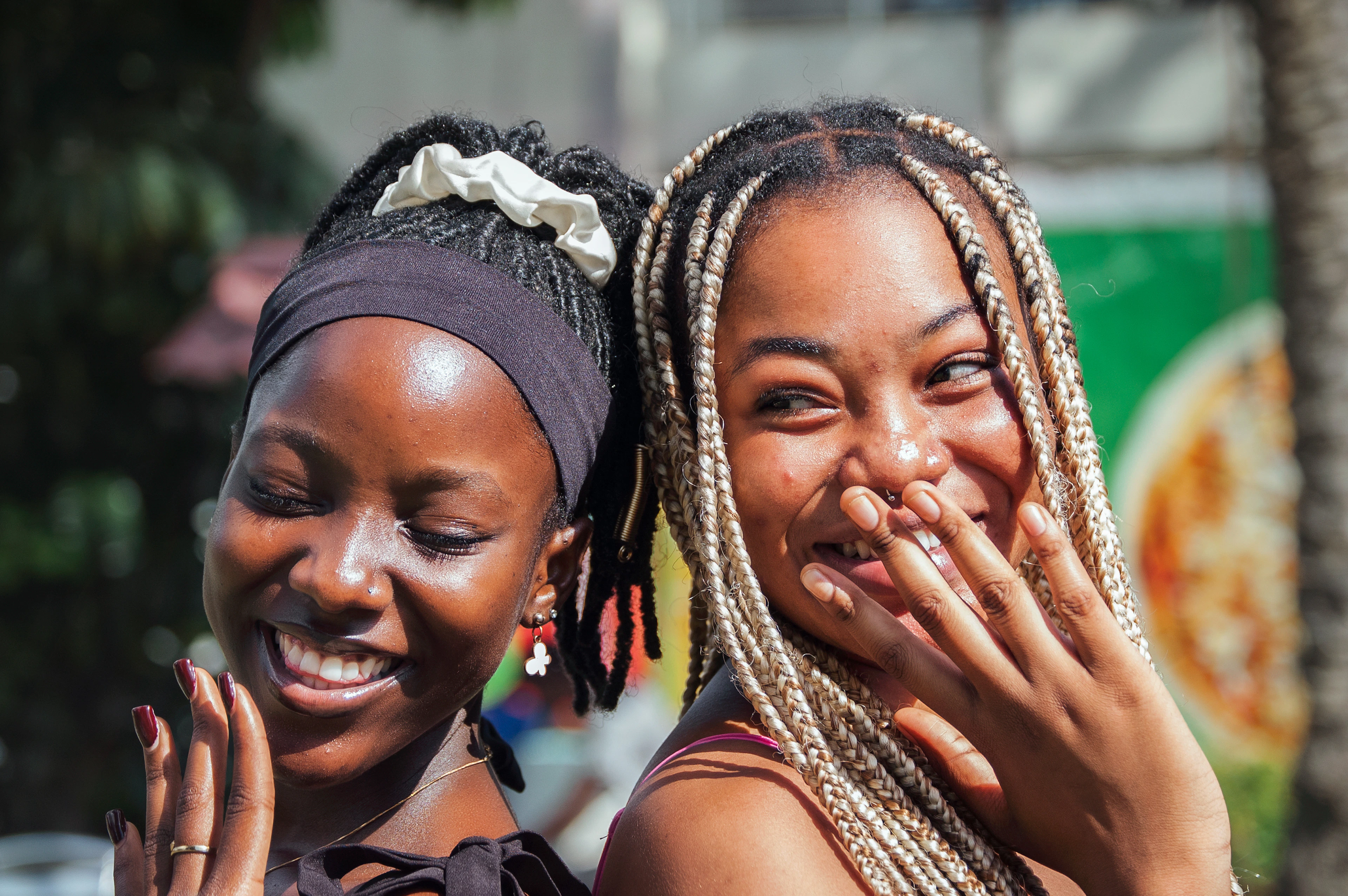 Two women sitting close together outdoors, both laughing