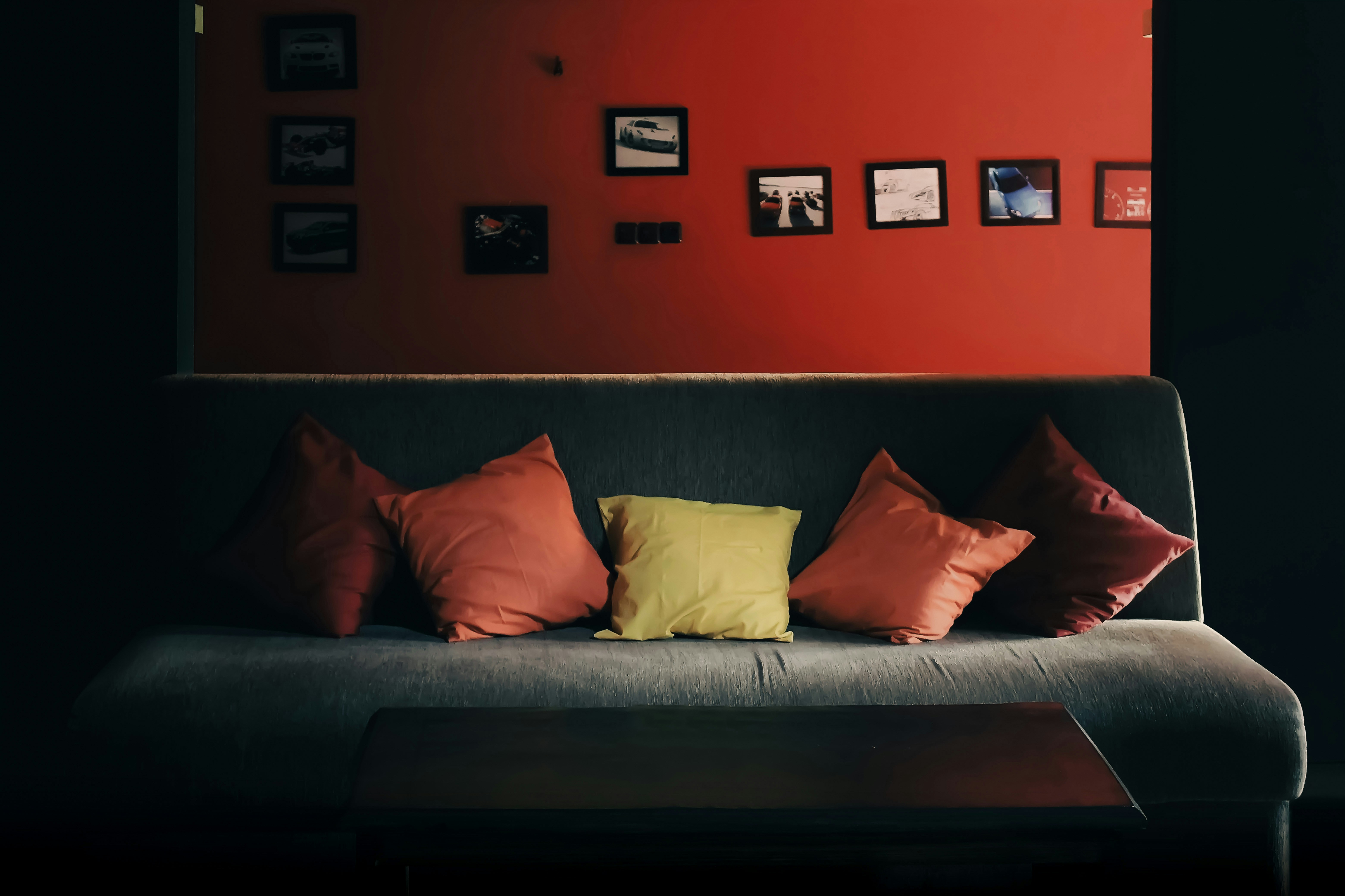 Cozy couch with pillows in front of a red wall.