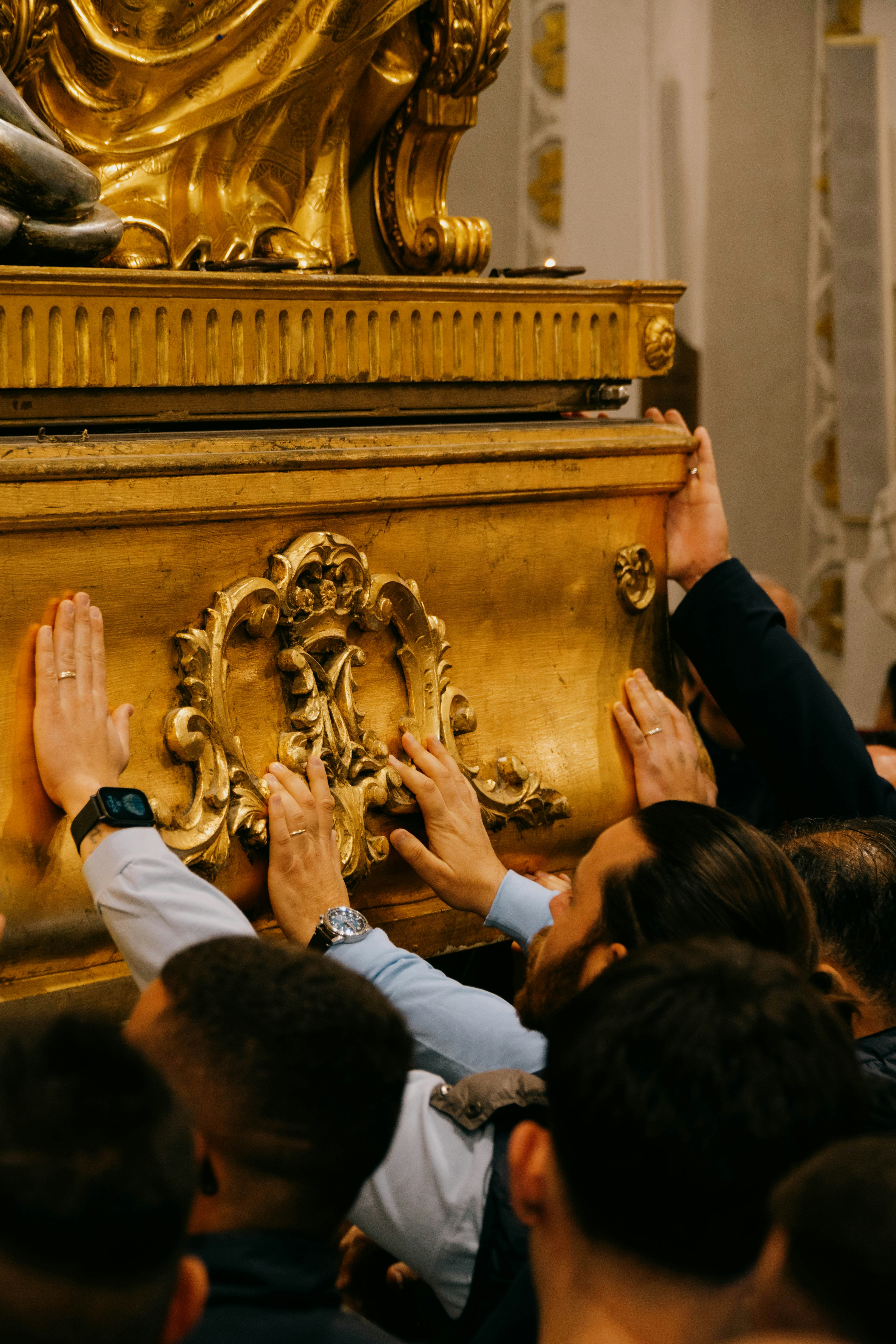 People carry a golden statue with their hands.
