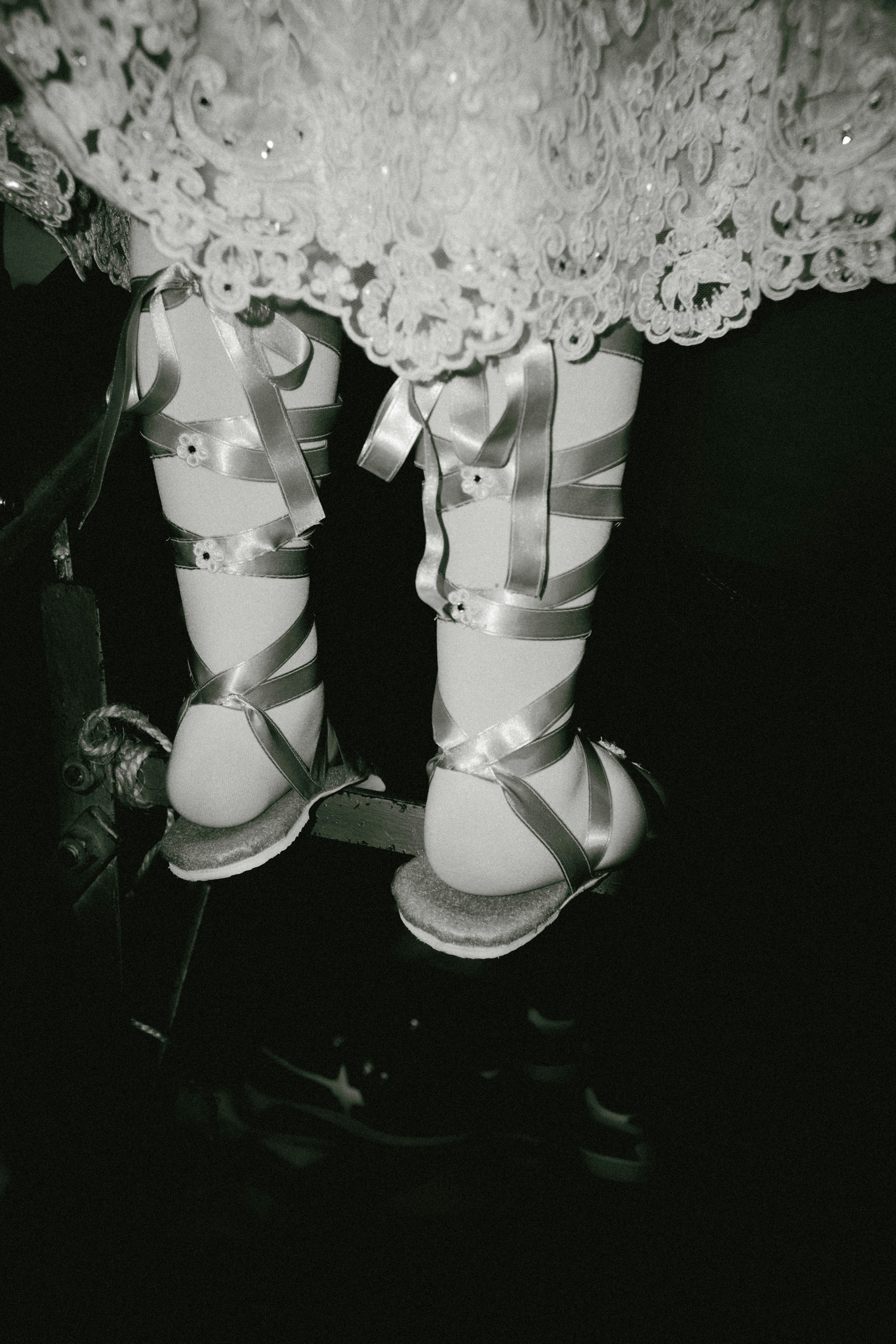 Tiny feet adorned with ribbons and sandals.