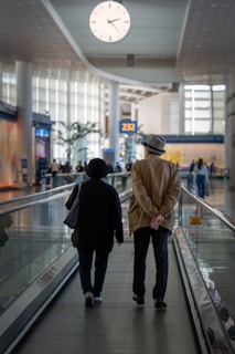 Couple walks through a busy airport terminal.