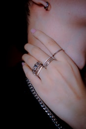 Rings and a chain necklace grace a hand.