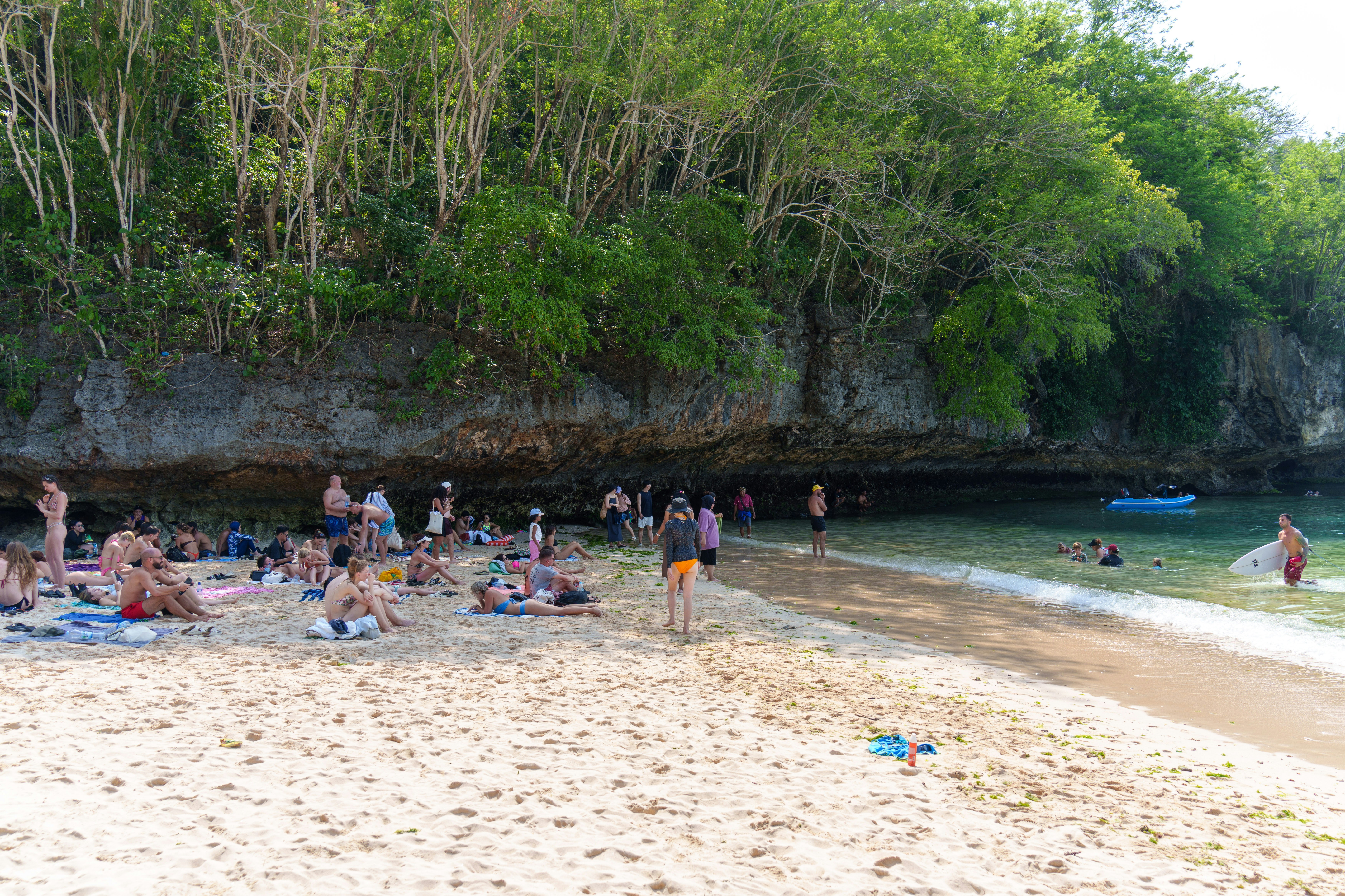People are sunbathing and swimming at the beach.