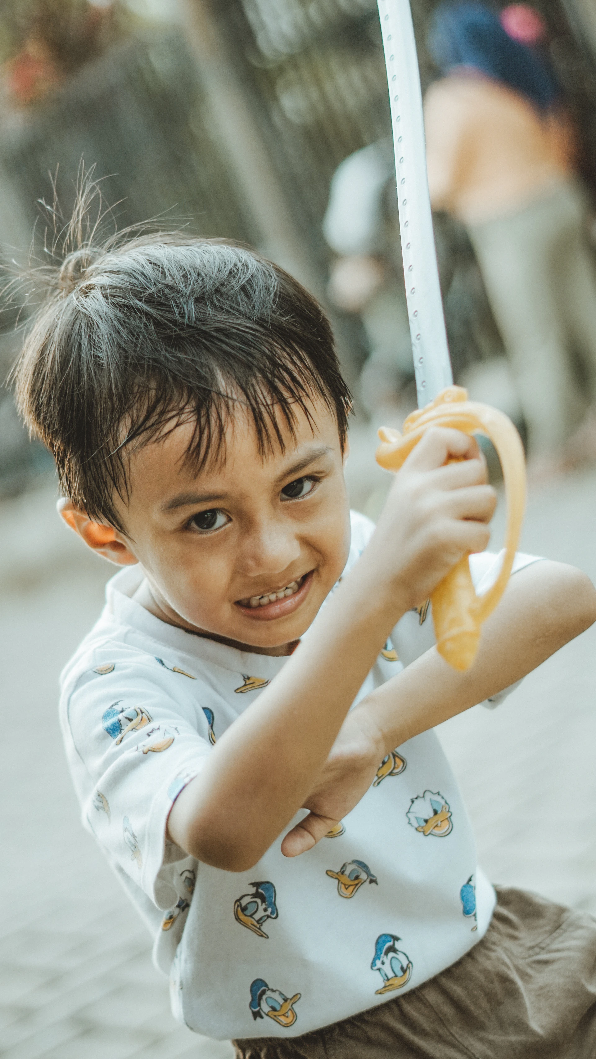 A boy smiles while holding a toy sword.