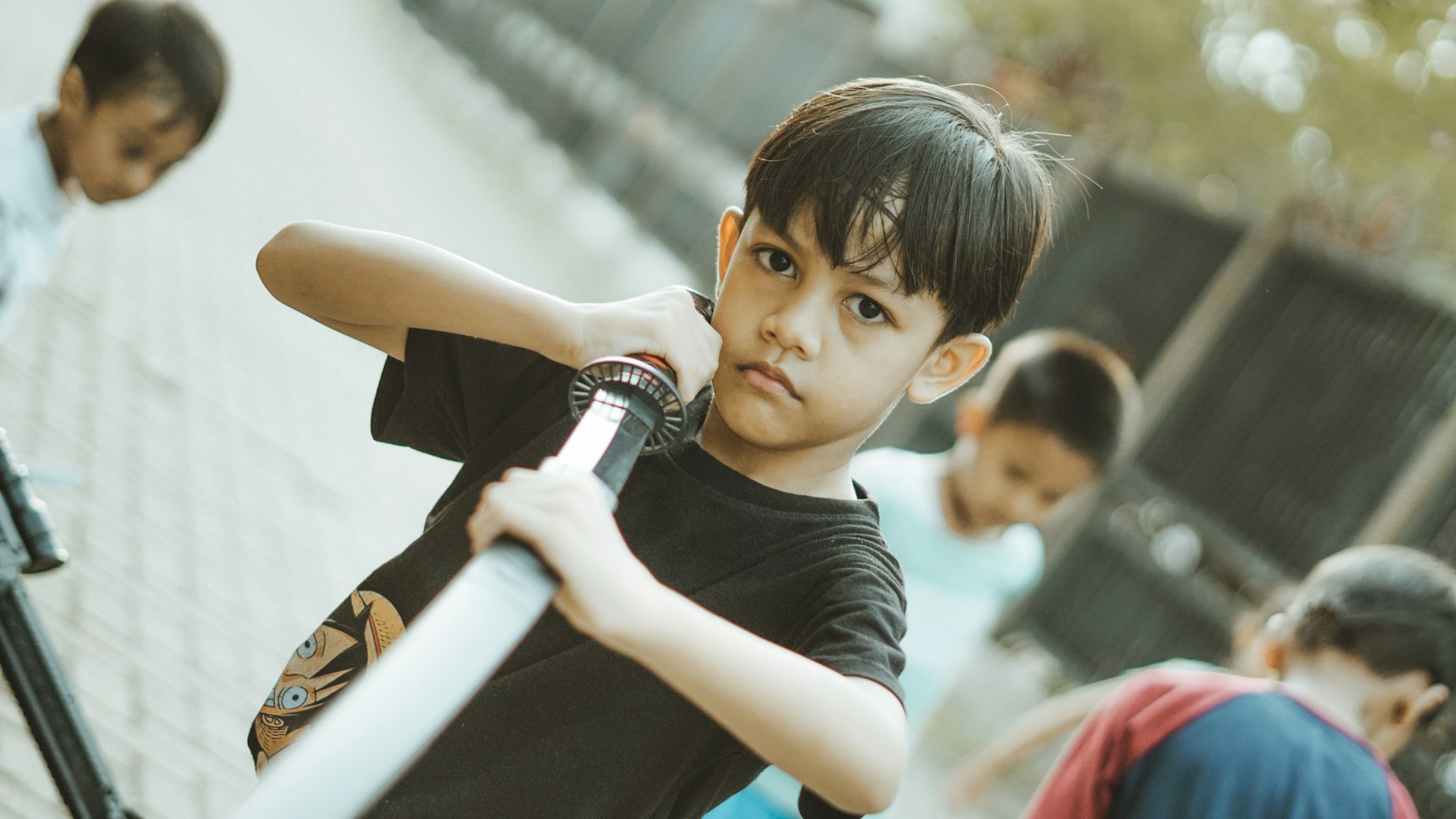 A boy plays cricket with other children.