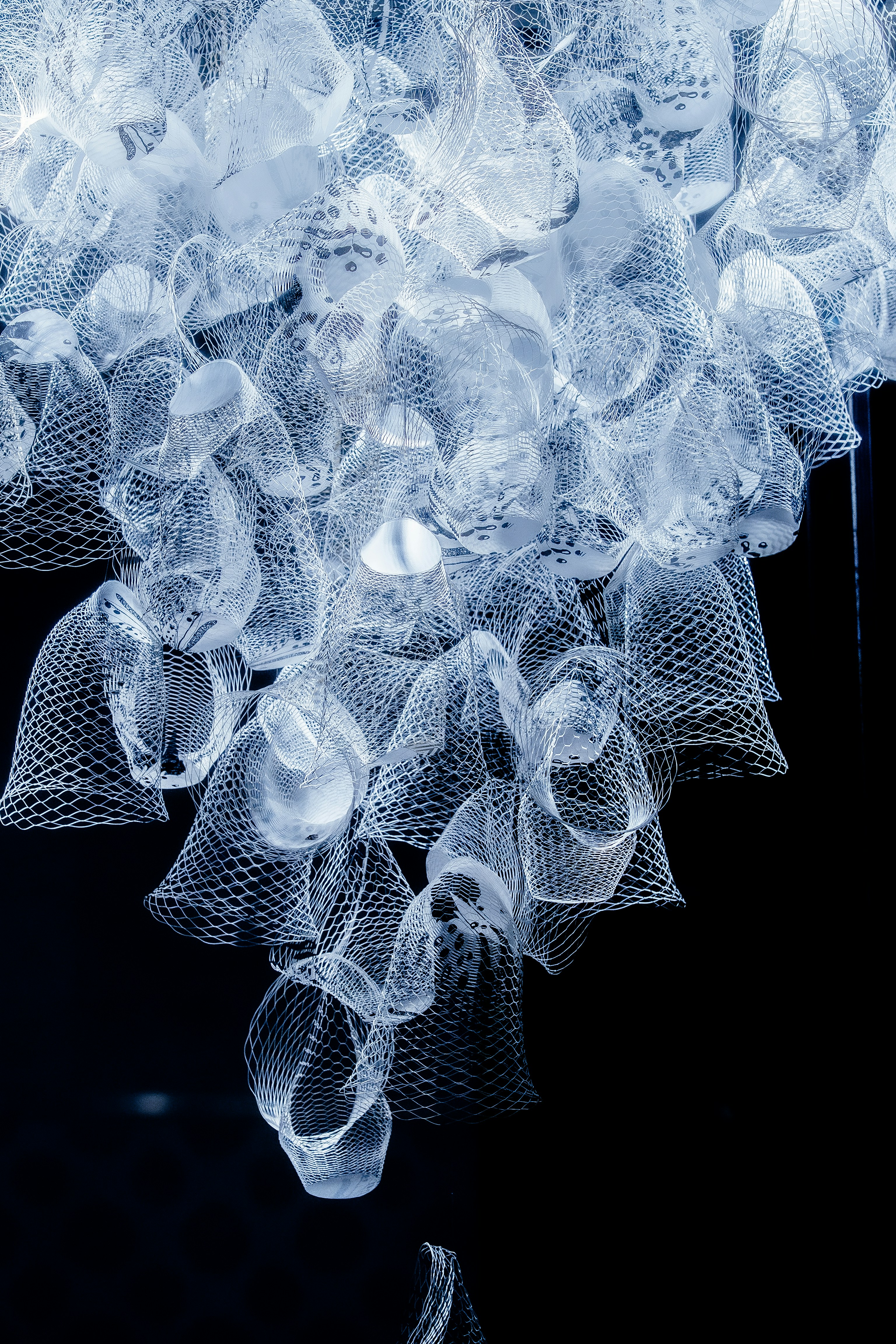 A decorative white installation hangs against black.