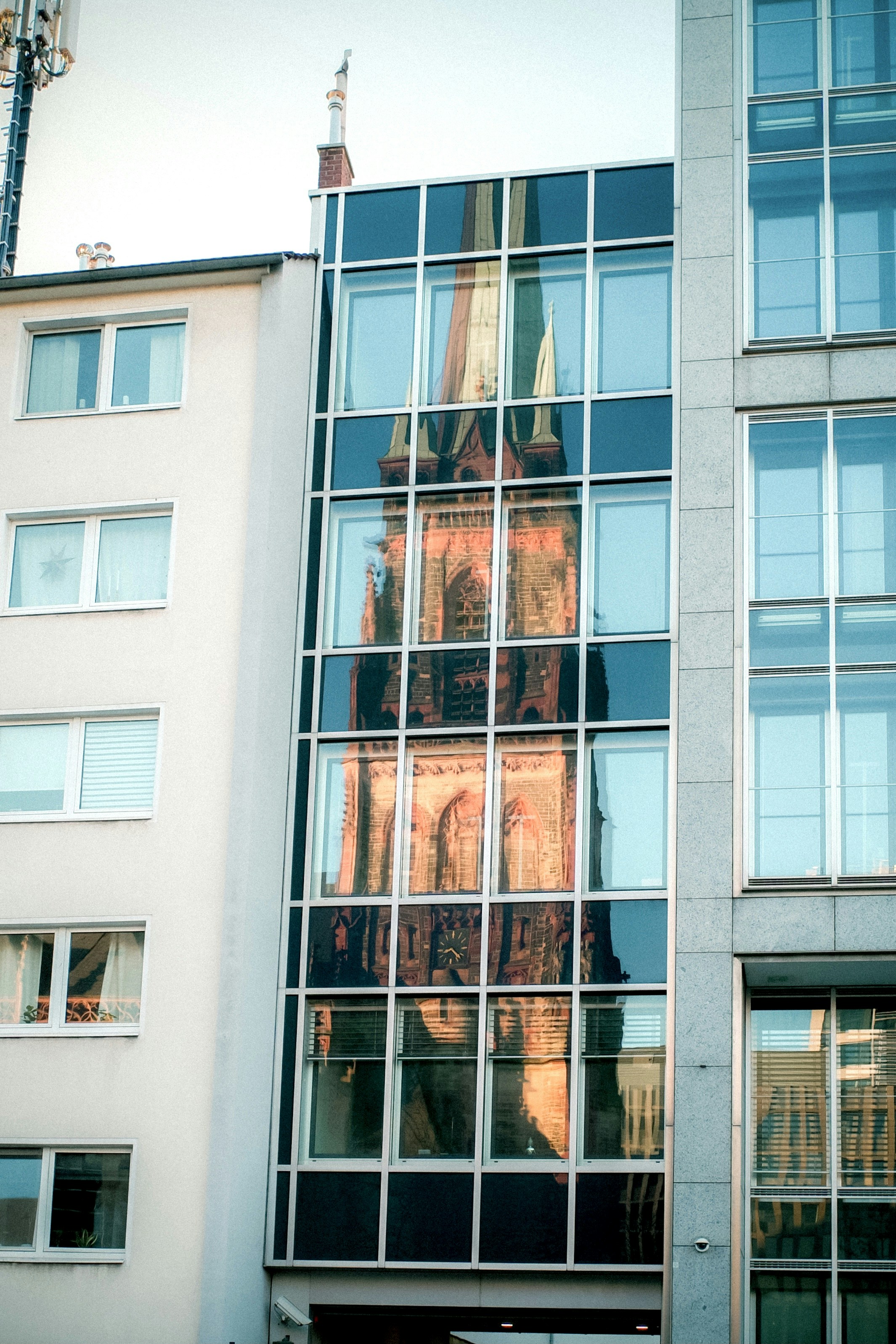 A church tower reflects in modern building's windows.