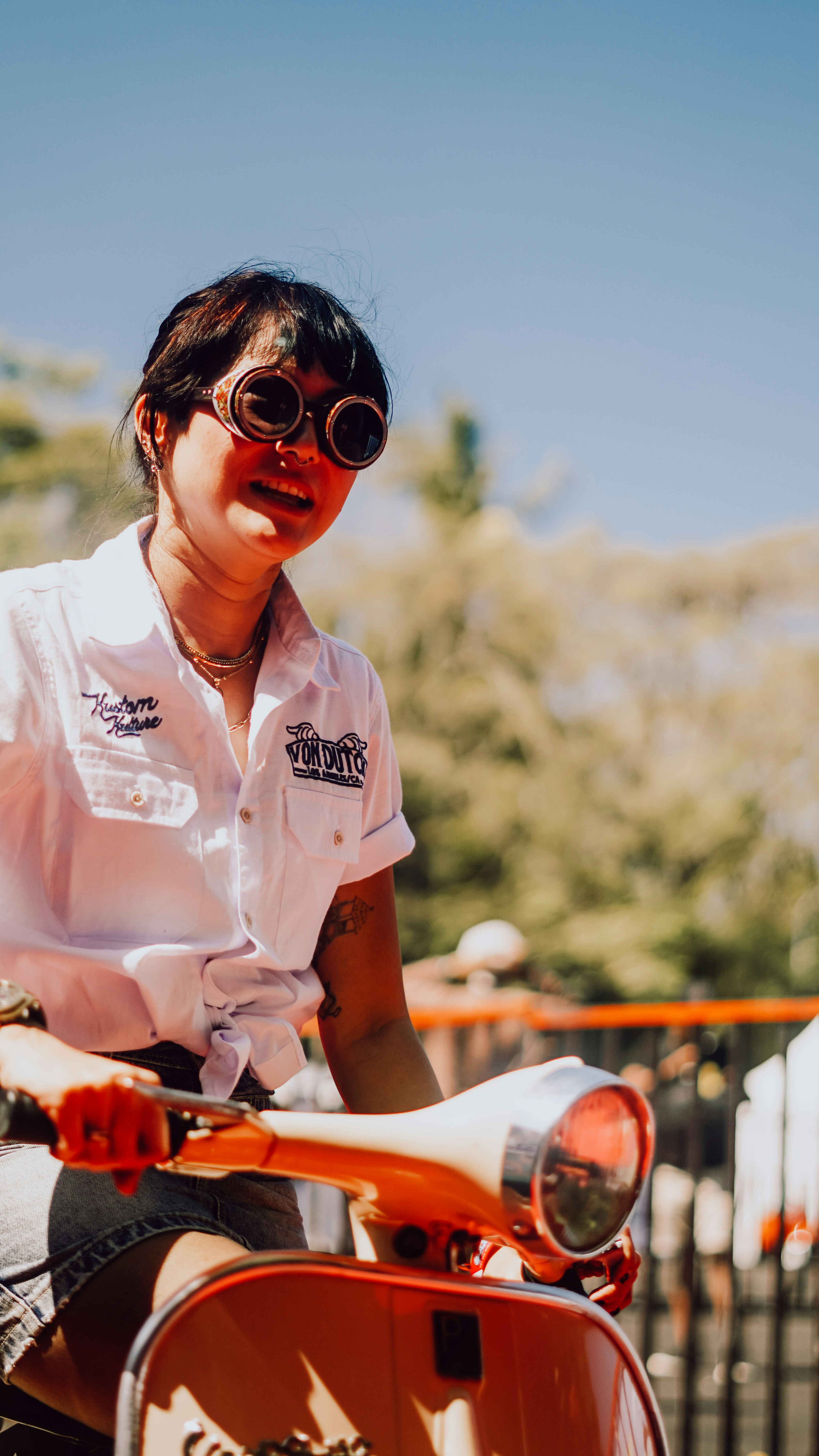Woman rides a vintage scooter wearing cool goggles.