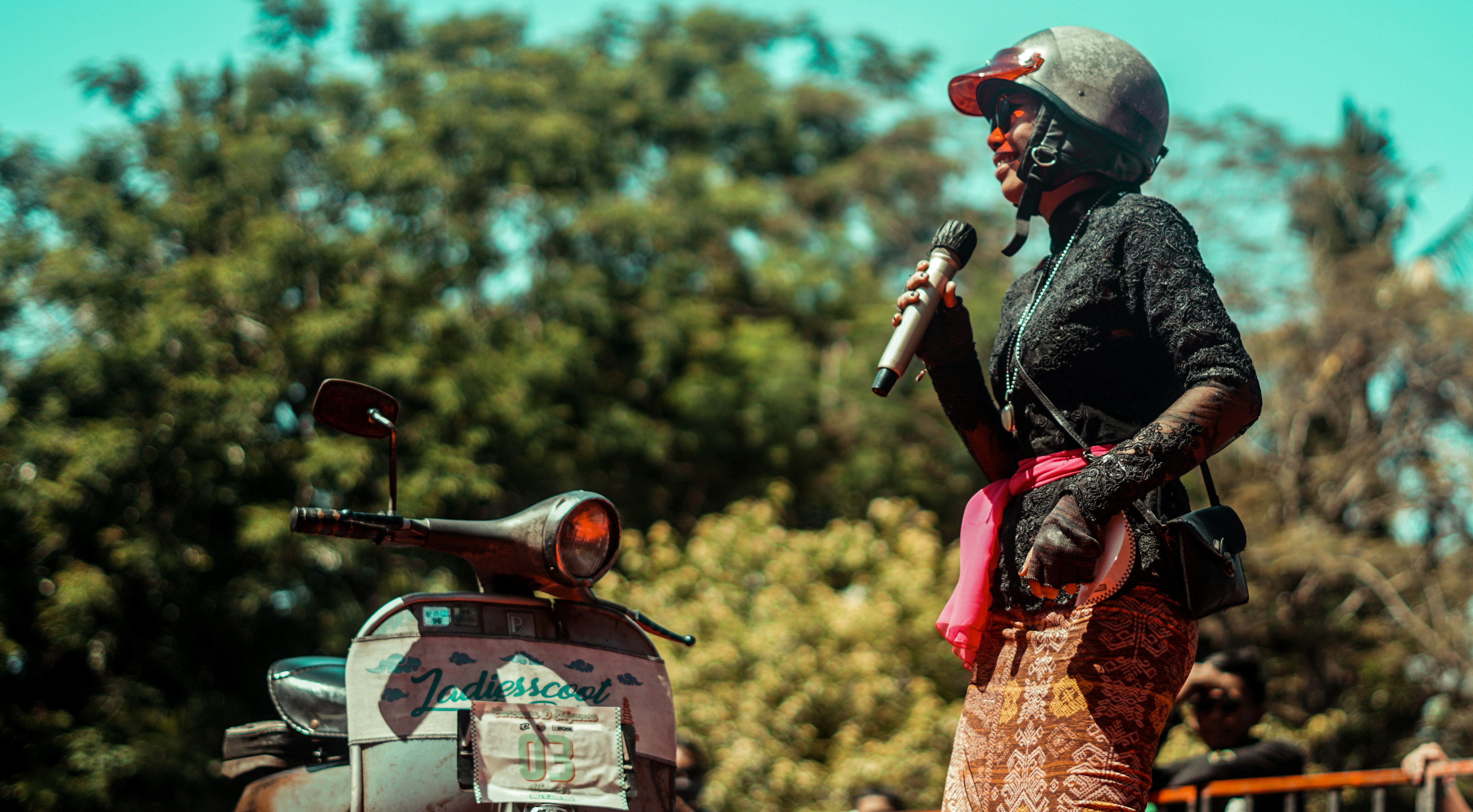 A woman in a helmet speaks near a scooter.