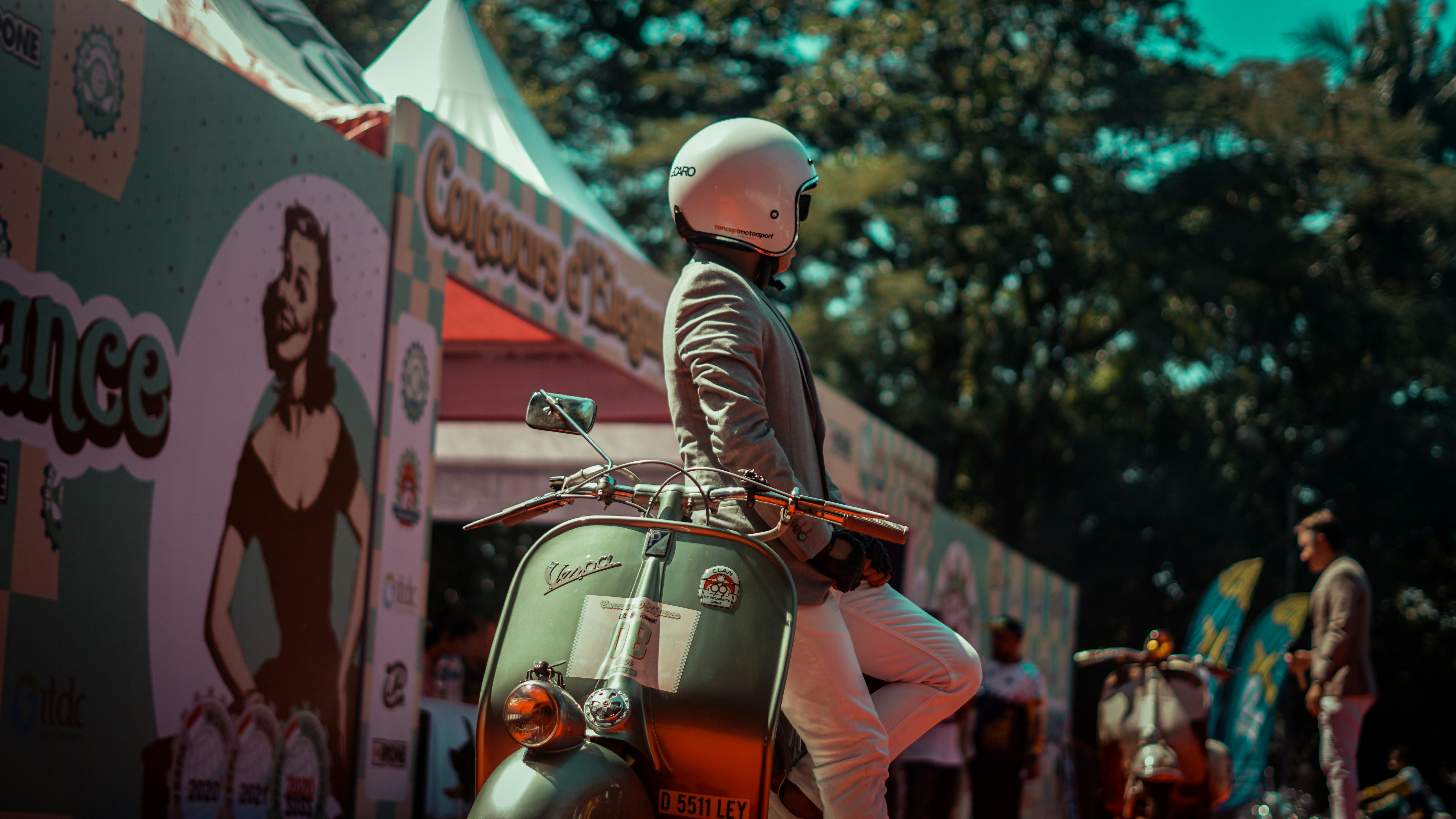 A person poses by a scooter at an event.