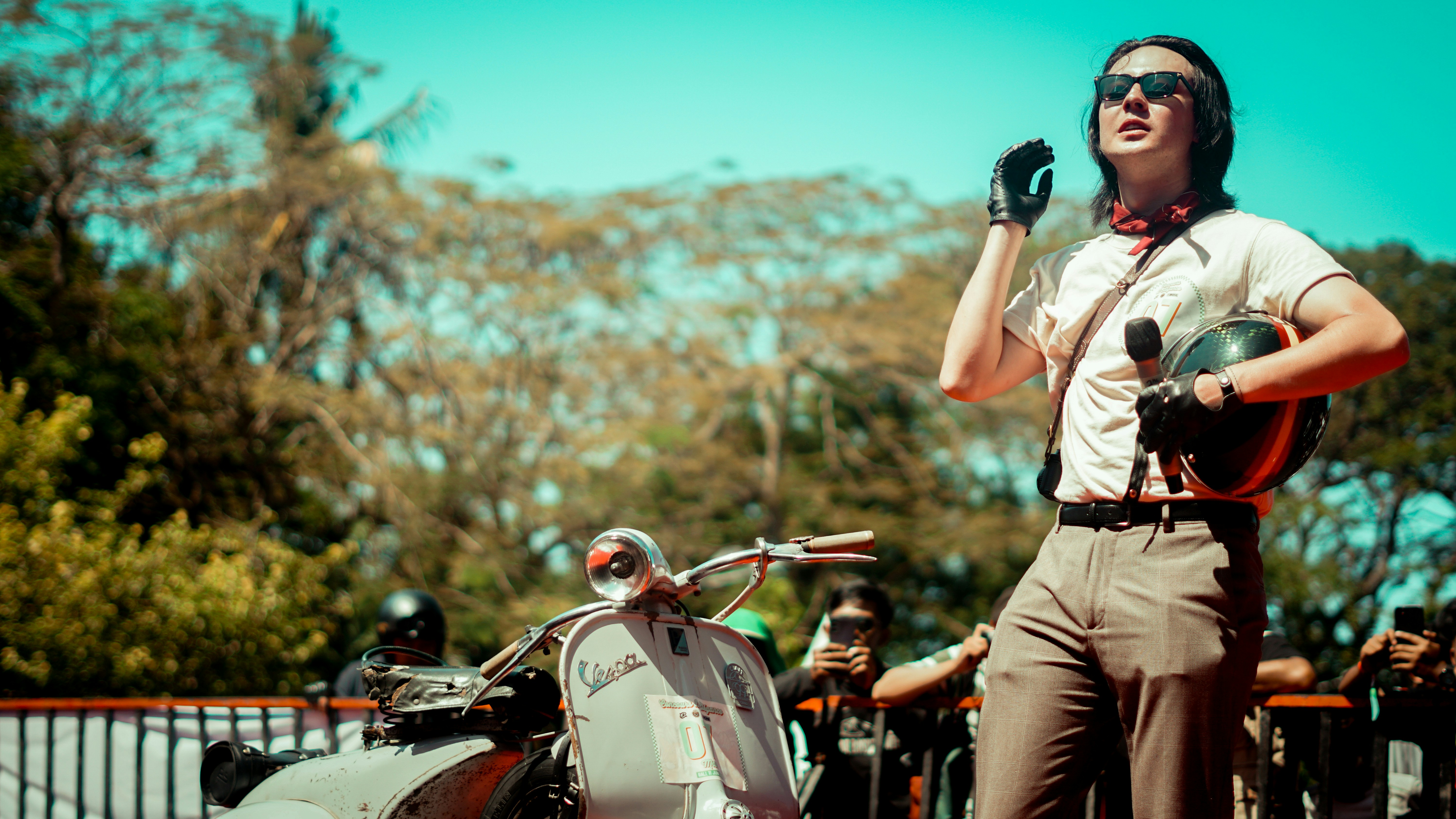 A man poses with his scooter outdoors.
