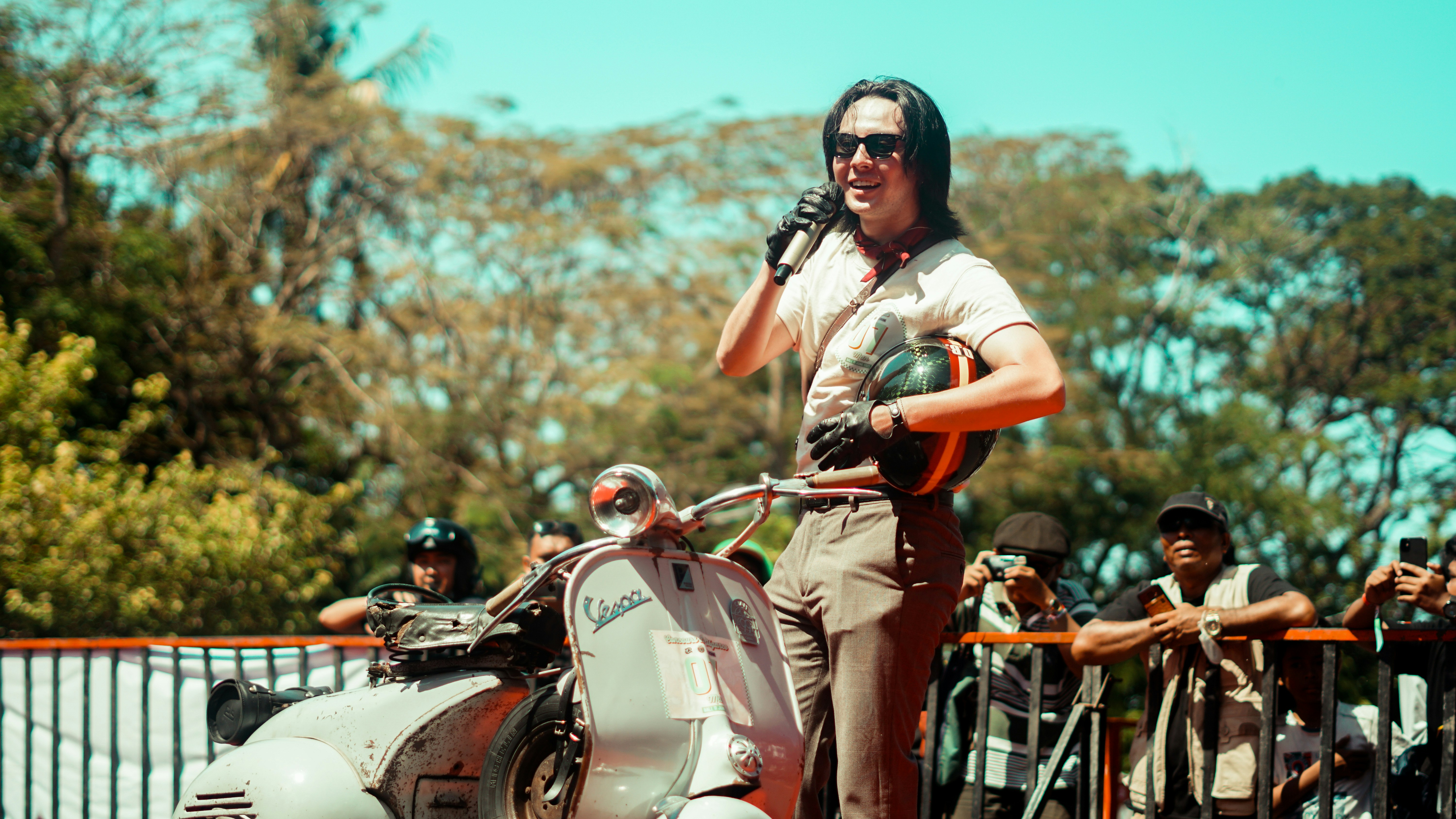 A man poses next to a vintage scooter.