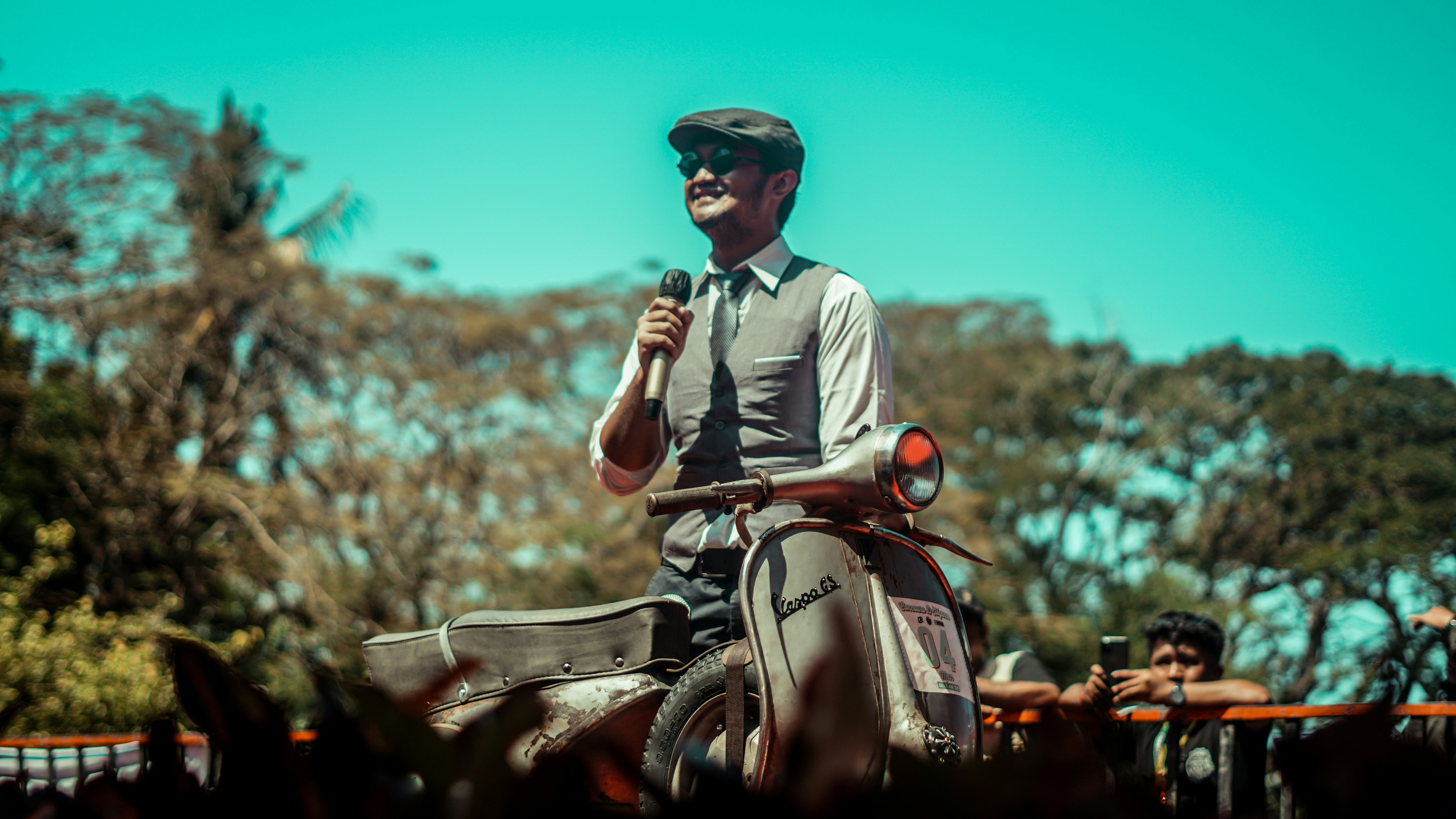 A man is speaking while riding a scooter.
