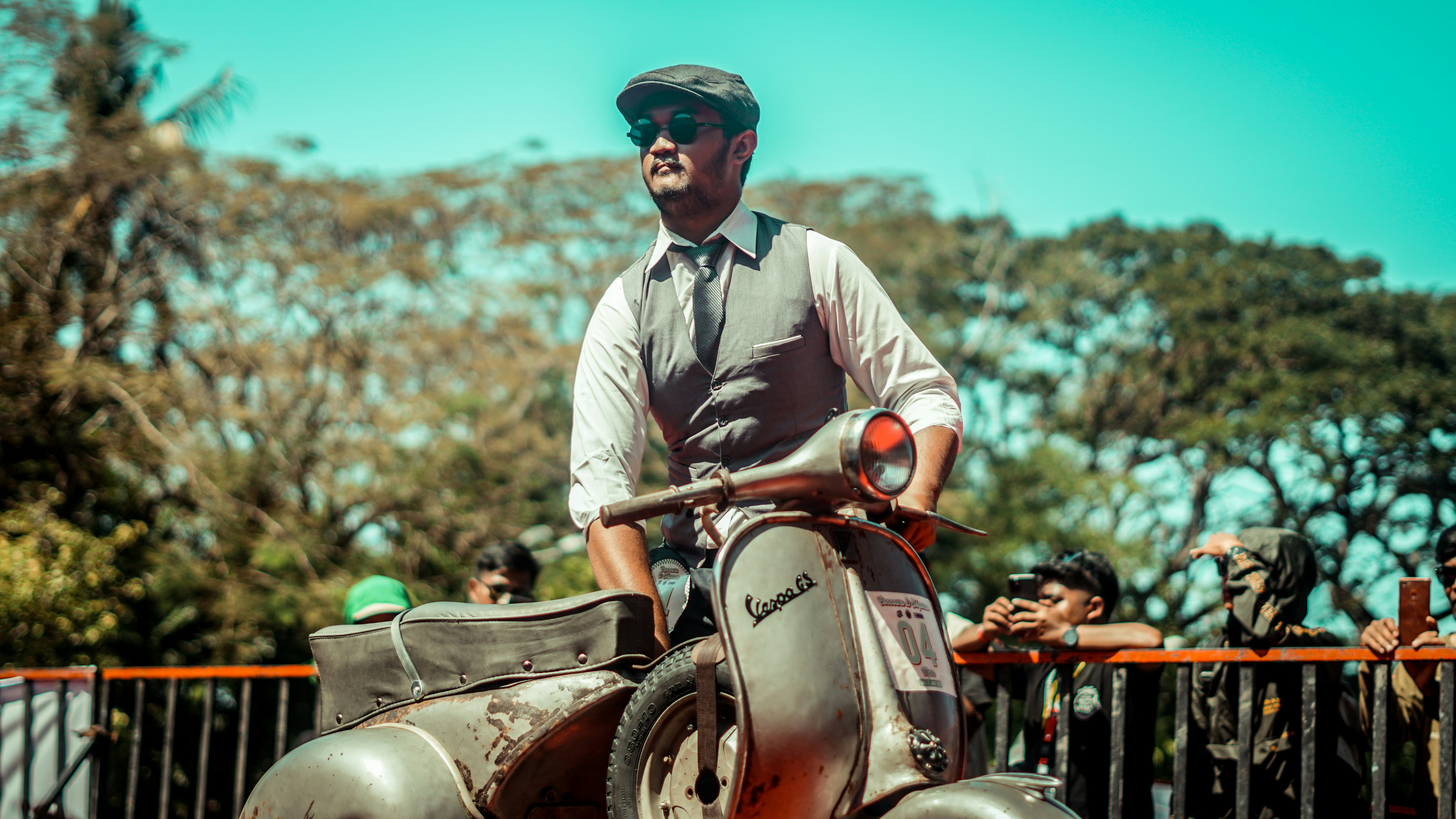 A dapper man rides a vintage scooter.