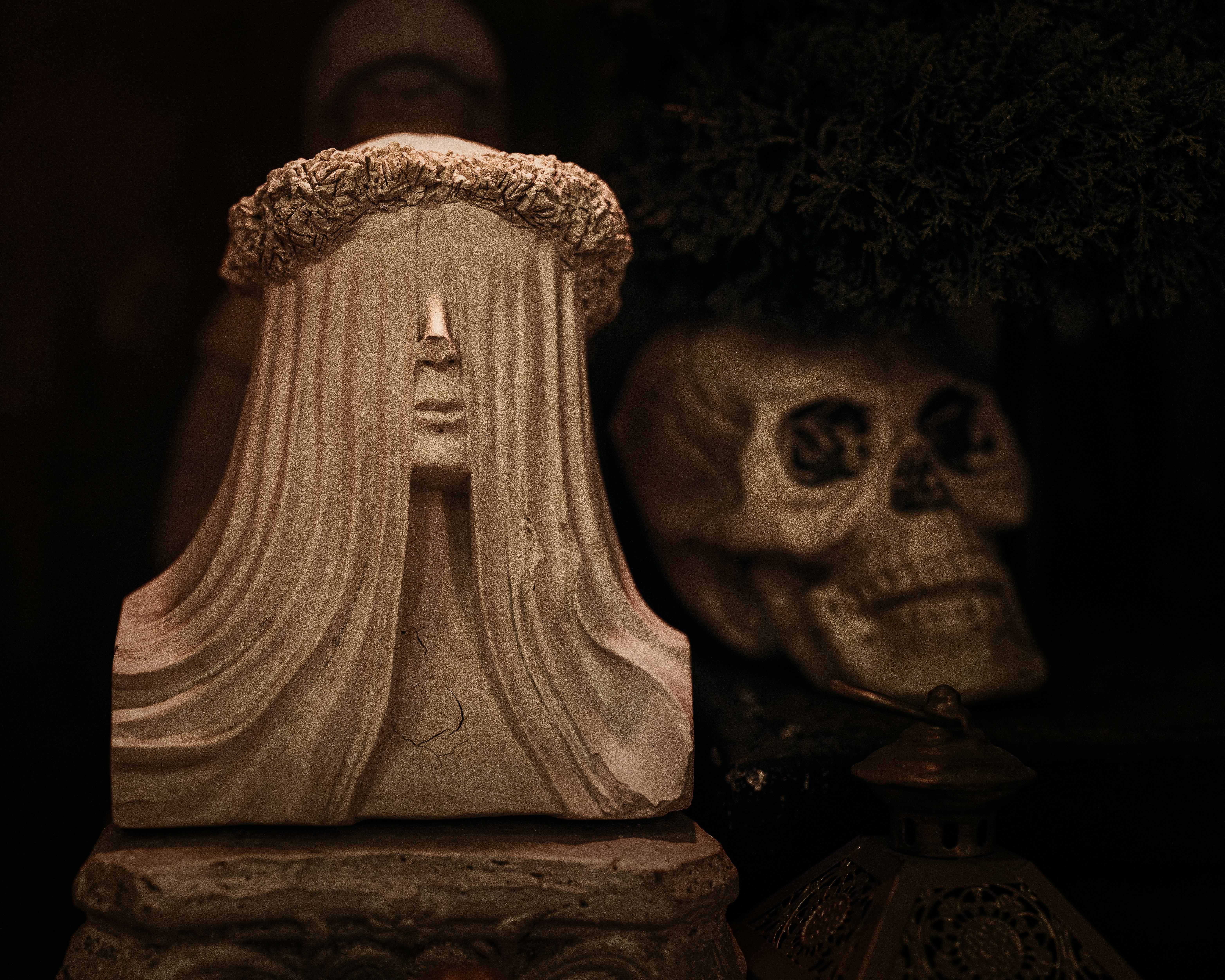 A statue and skull create a spooky, dark scene.